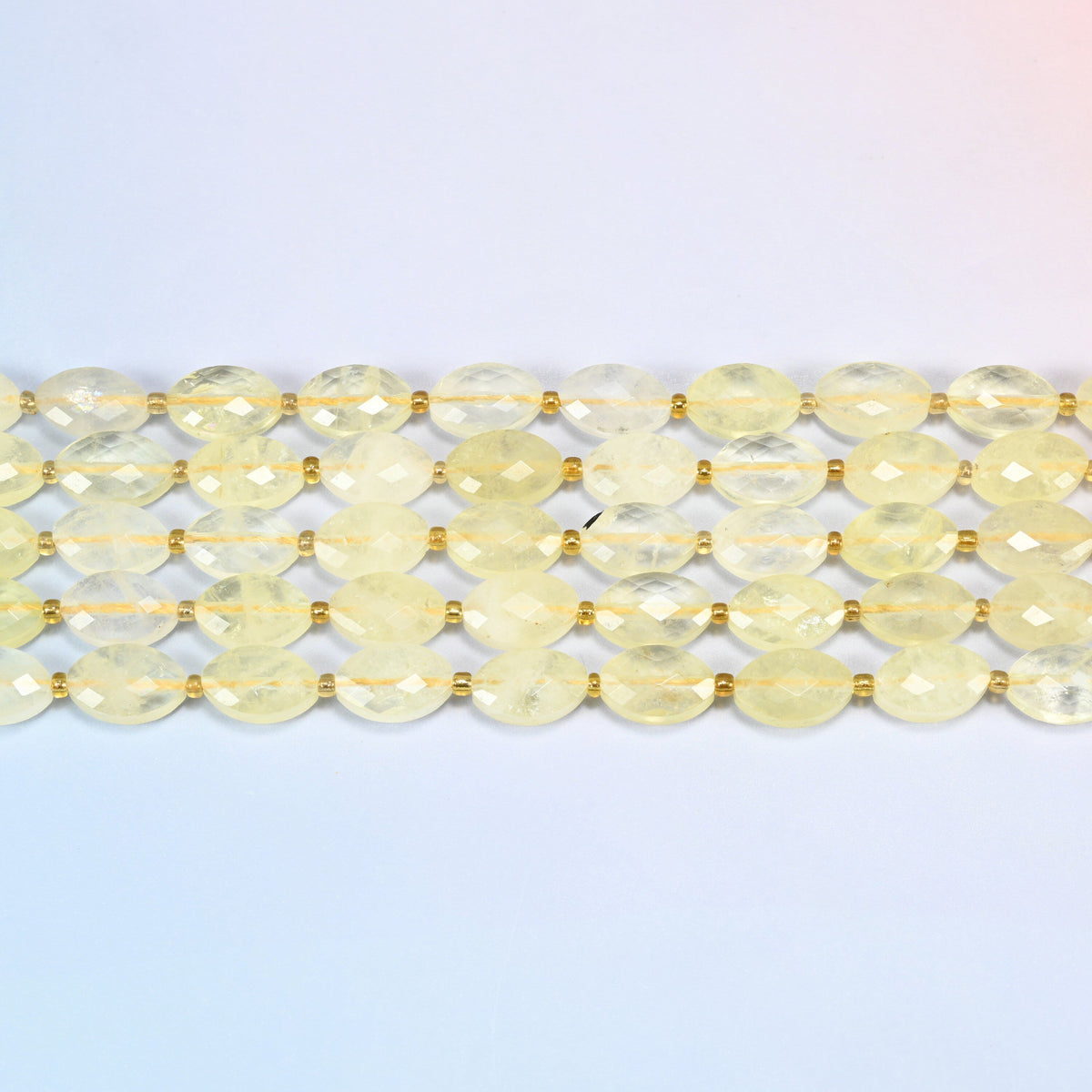 Several strands of citrine faceted flat oval beads laid in straight rows with gold seed bead spacers