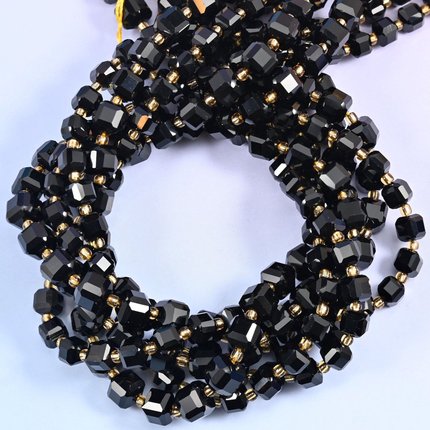 Solid jet black cubes with the corners cut away into facets, polished to a hard mirror gloss that picks up a white highlight on every face. Dense