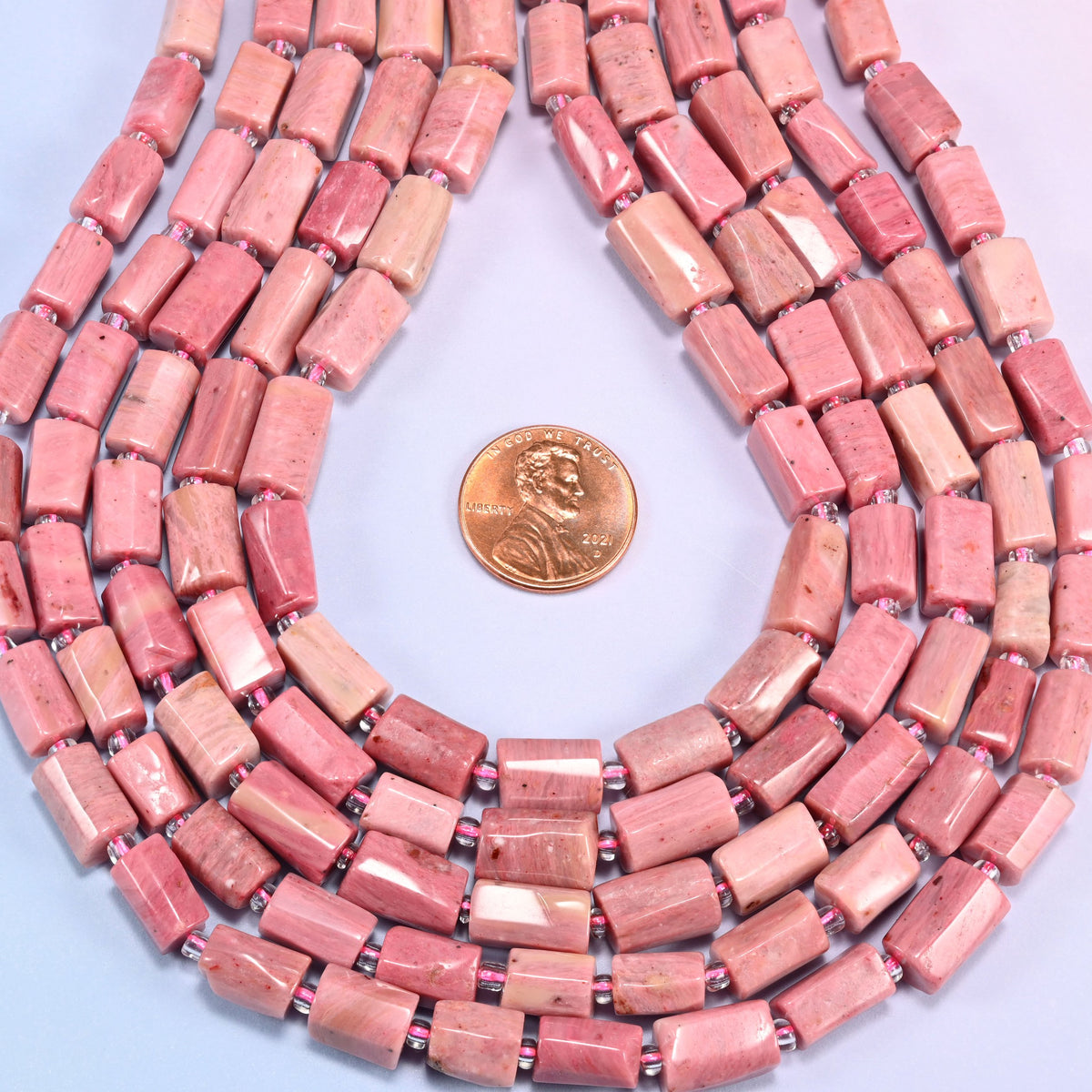 Pink Rhodonite faceted tube beads in a teardrop coil, bead length running 9mm to 11mm along the strand at a steady 7mm width