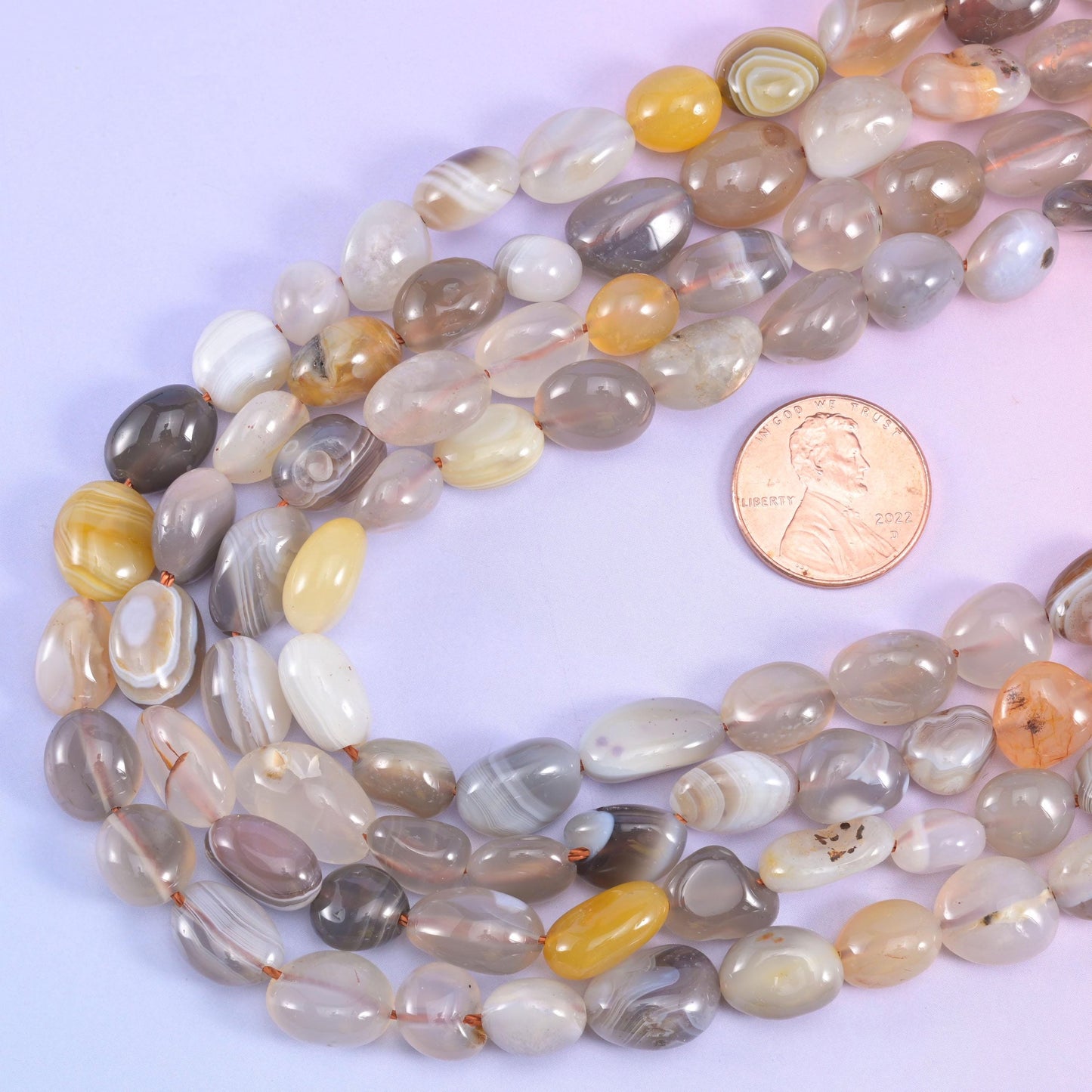 Botswana Agate nugget strands looped beside a US penny for size comparison
