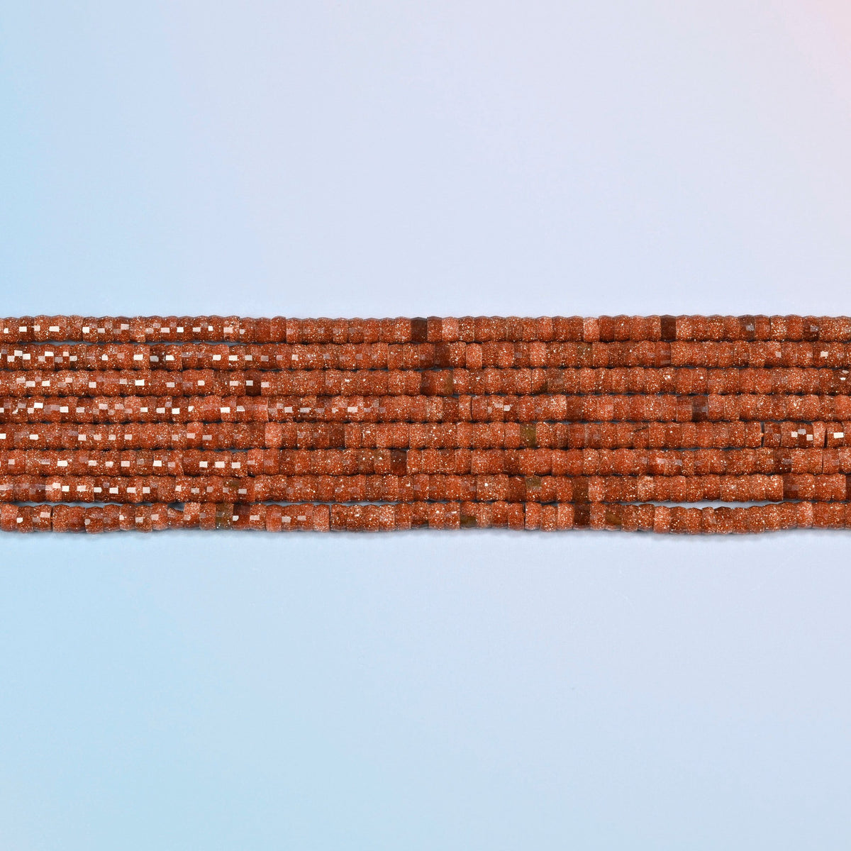 Several strands of gold sandstone faceted heishi disc beads laid in straight rows