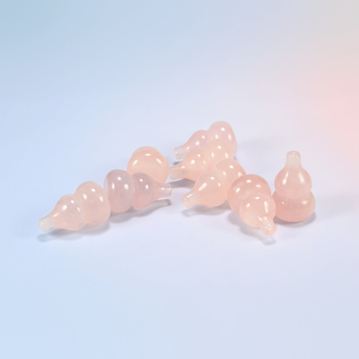 A pile of small natural rose quartz gourd carvings, light pink