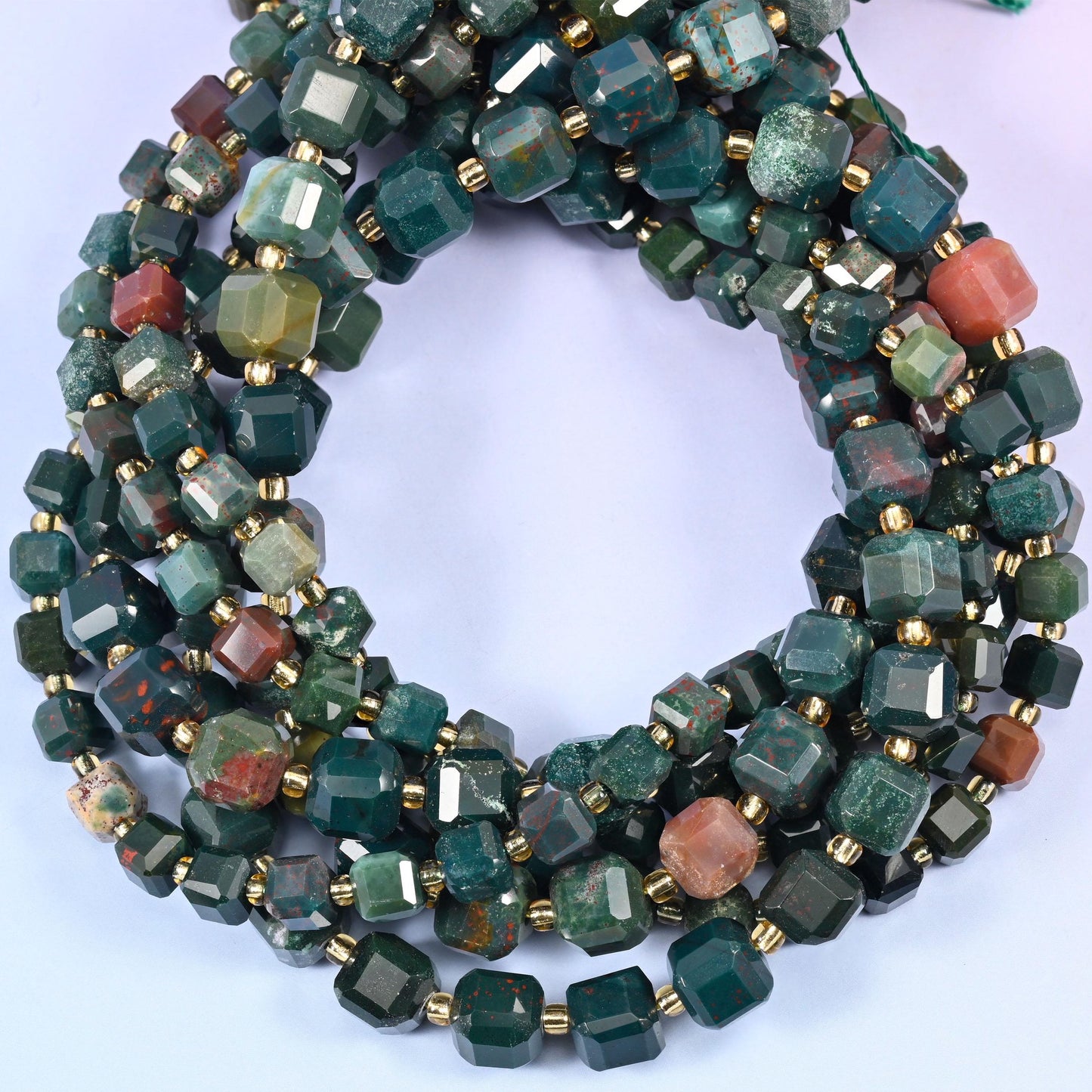 Deep forest and sea green mottled with dark grey, broken up by the occasional coral-pink or rust bead, each cube faceted on every side.