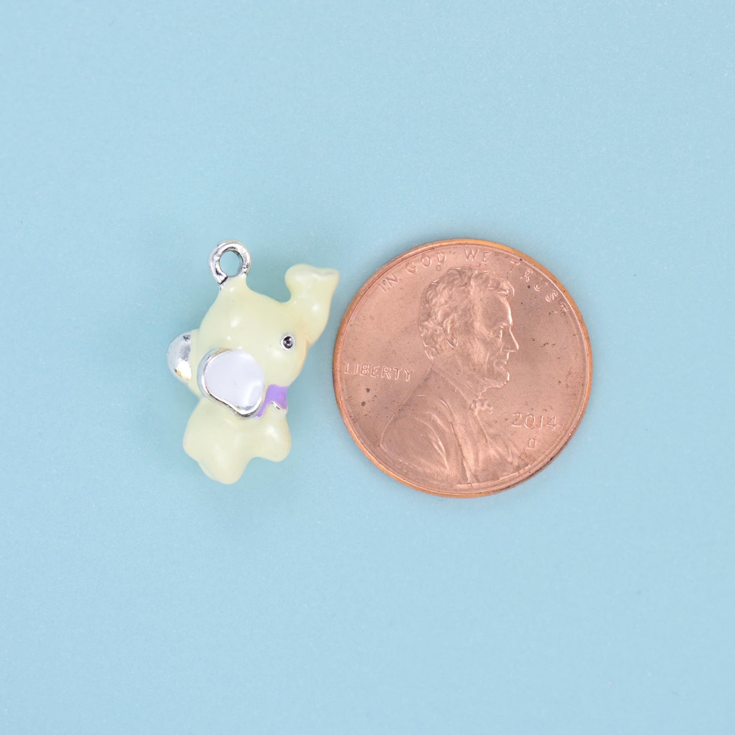 A chubby little elephant modelled fully in the round rather than stamped flat — glossy pastel enamel in baby pink, powder…