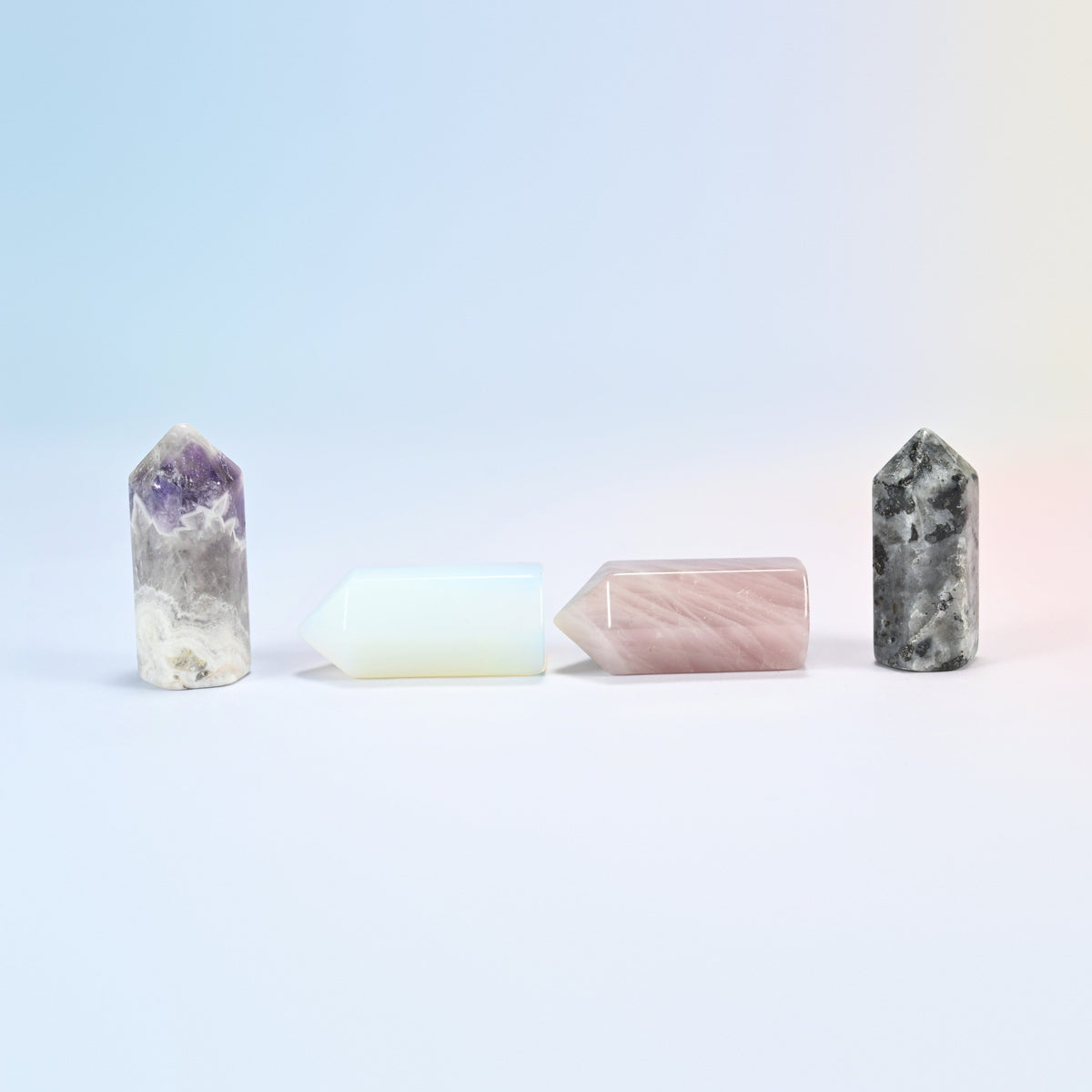 Small amethyst and black labradorite crystal points standing with opalite and rose quartz points lying down