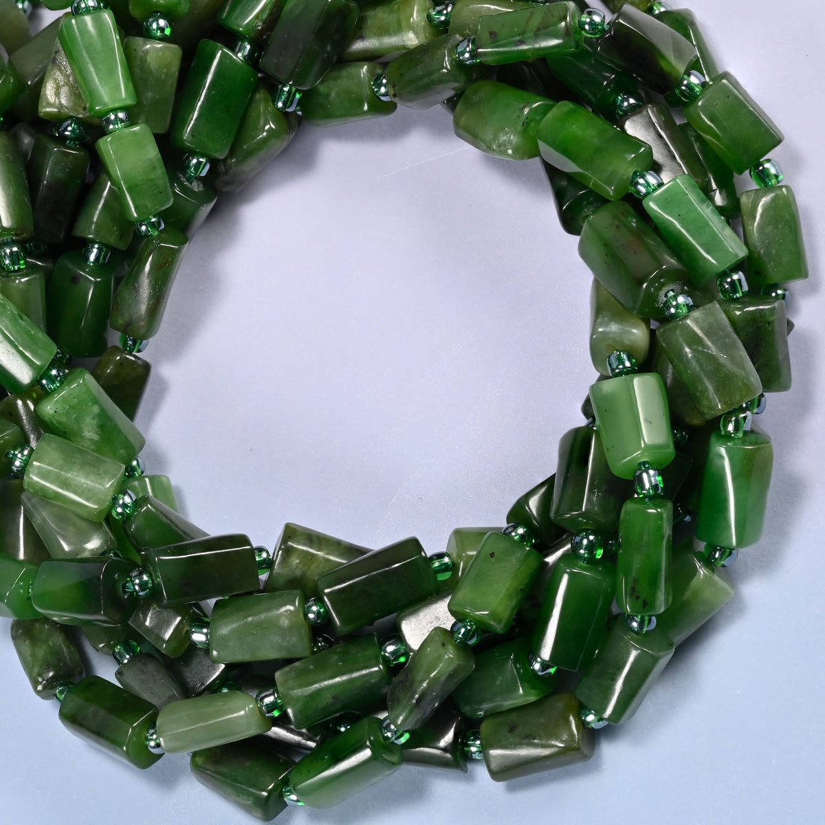 Canadian Green Jade faceted tube beads coiled into a ring, colour running from solid dark green to pale sage from bead to bead