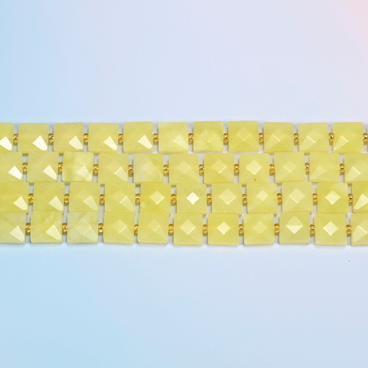 Several strands of Lemon Jade faceted flat square beads laid in straight rows
