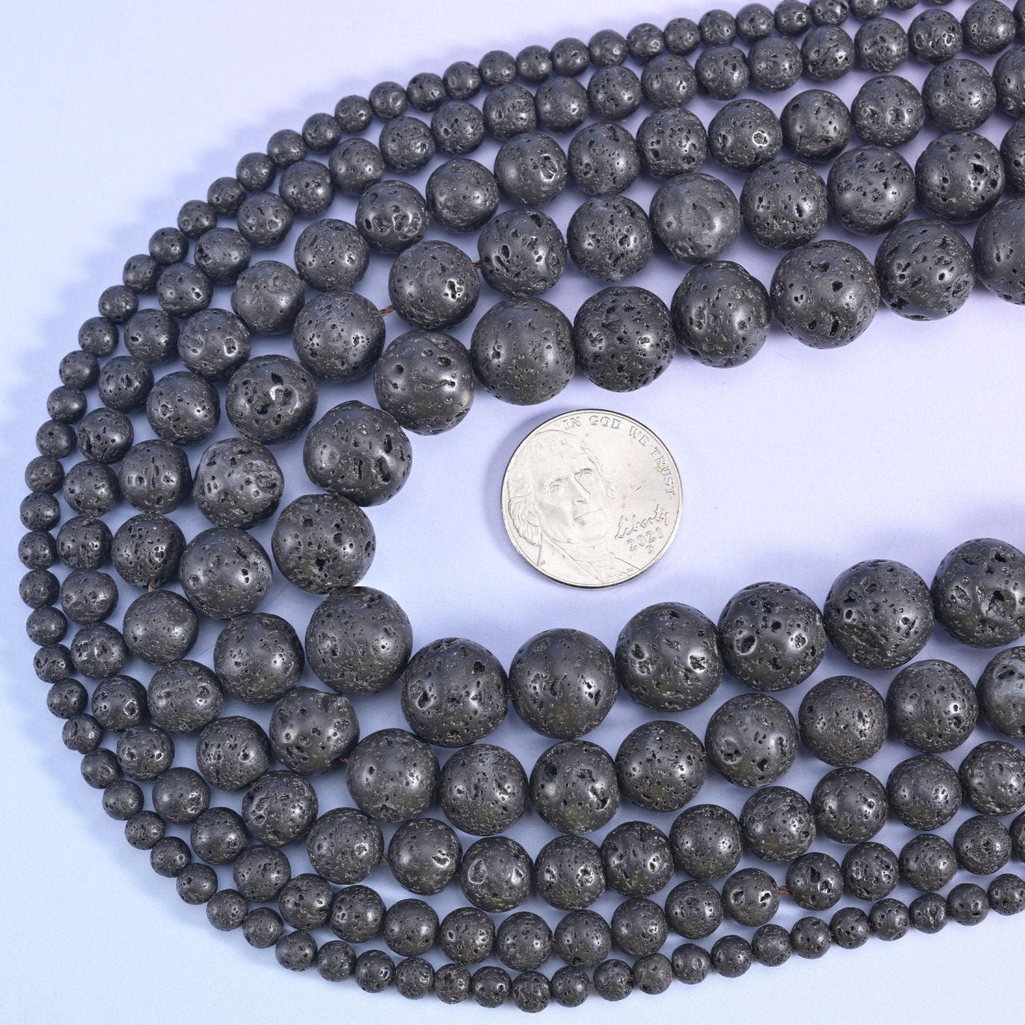 Matte charcoal black and deeply pitted all over, keeping the open porous surface of volcanic stone