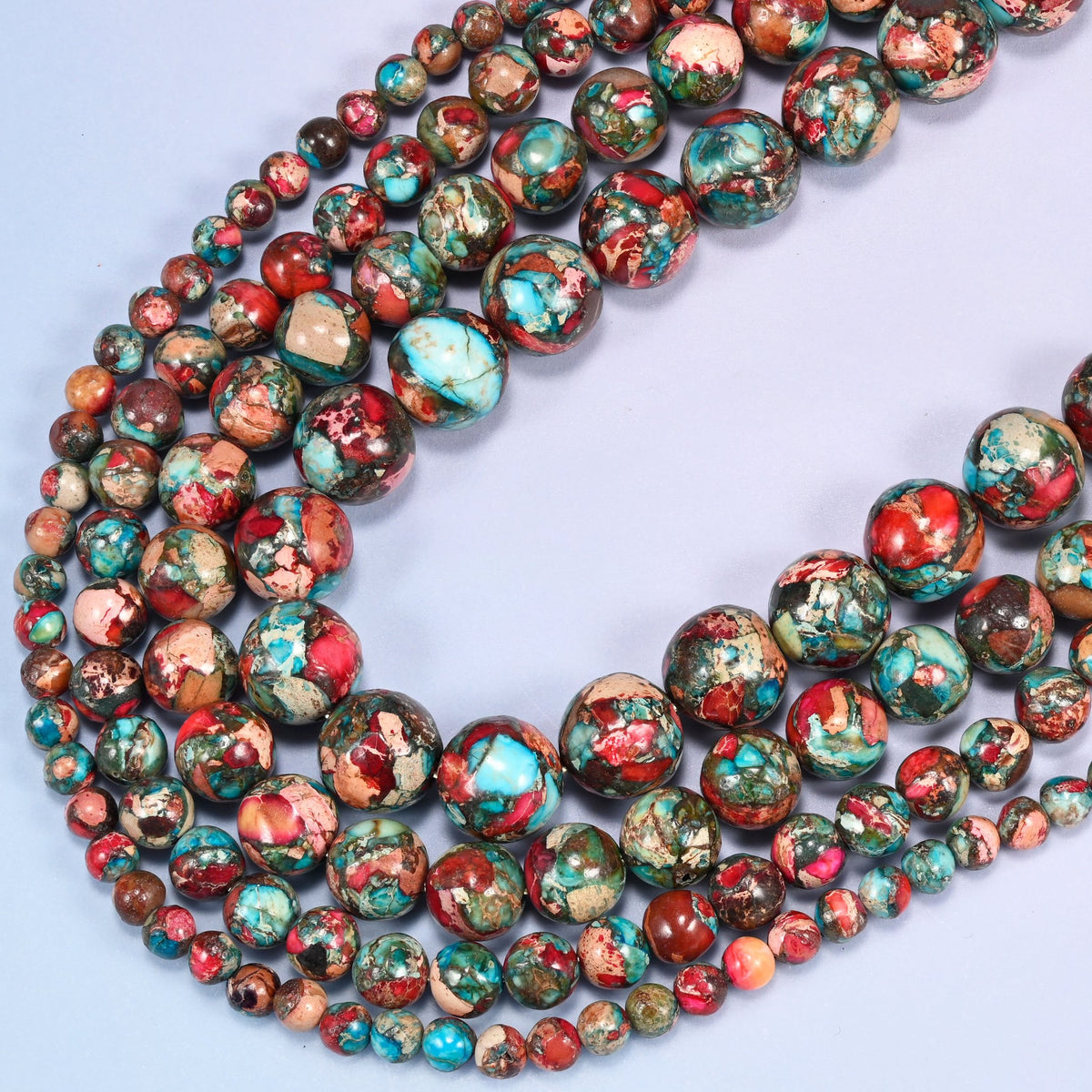 Red sea sediment jasper round beads, several strands looping in a wide curve across the frame.