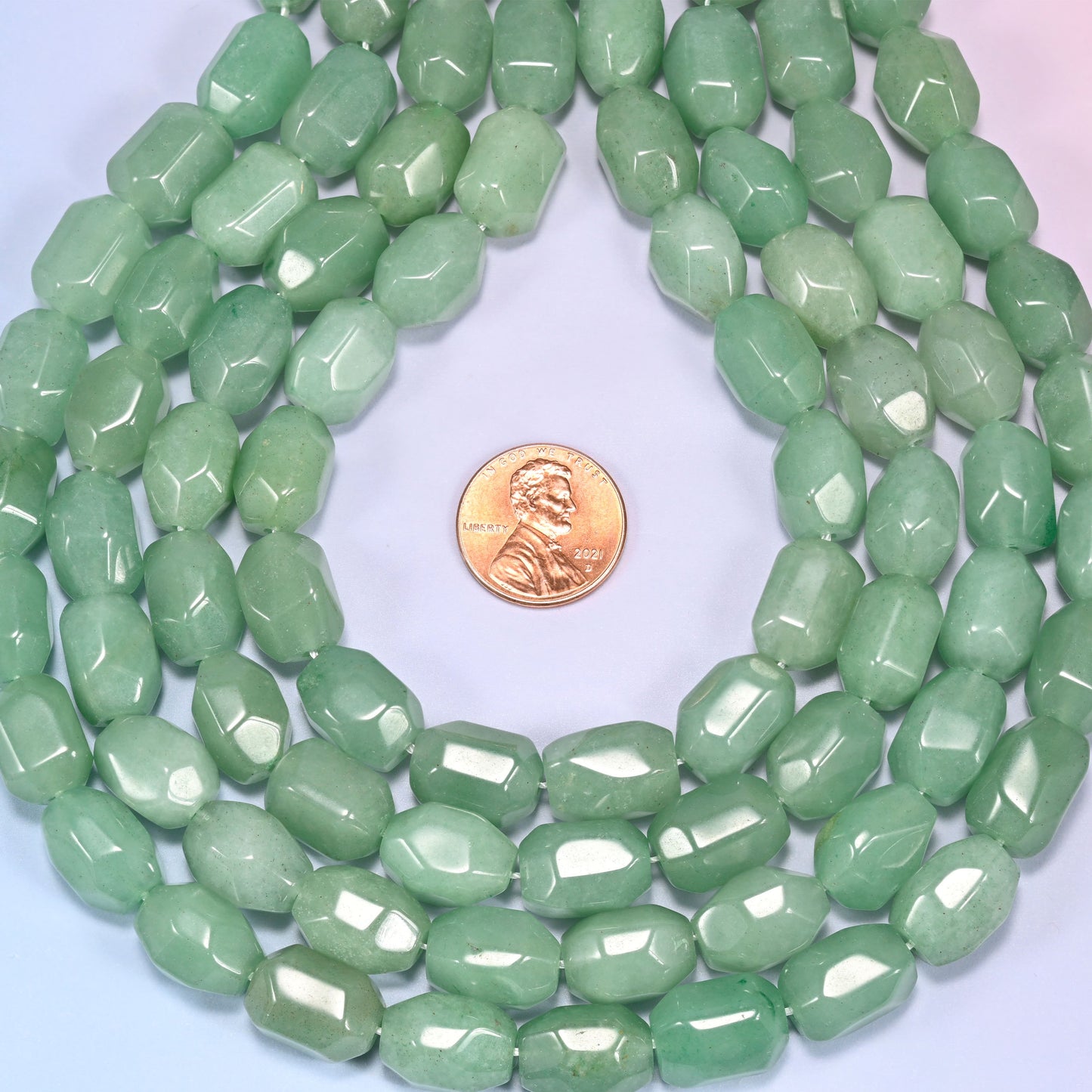 Wide circular coil of green faceted Aventurine barrel beads on a light background, showing the dense wreath pattern.