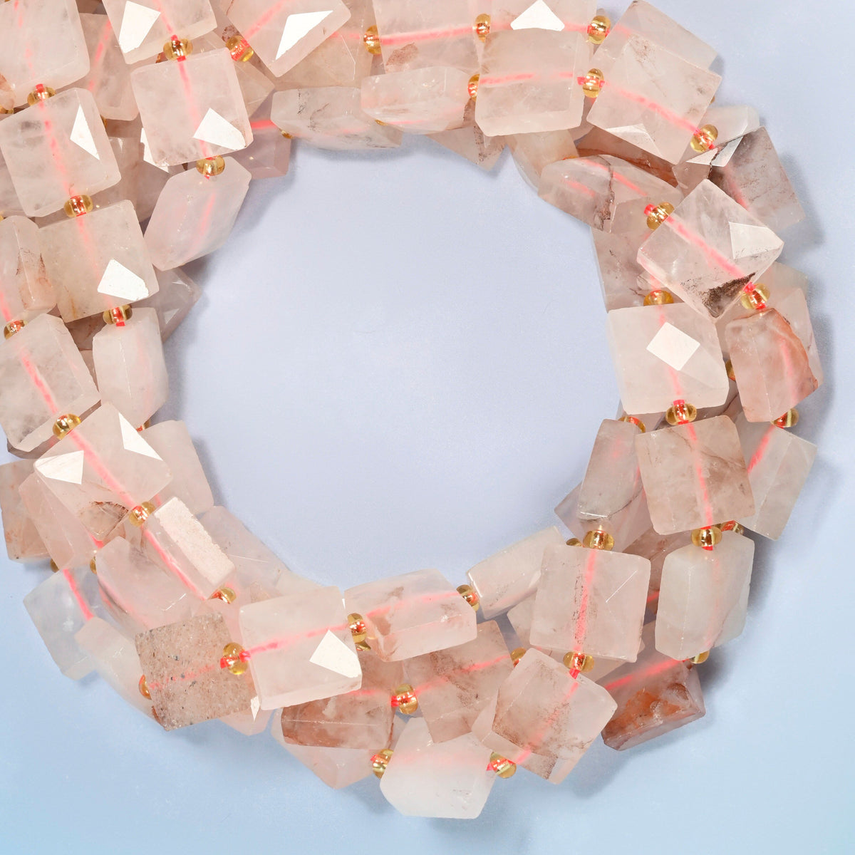 Natural red hematoid quartz faceted flat square beads coiled into overlapping loops, whole strands of frosted pink stone streaked with red-brown