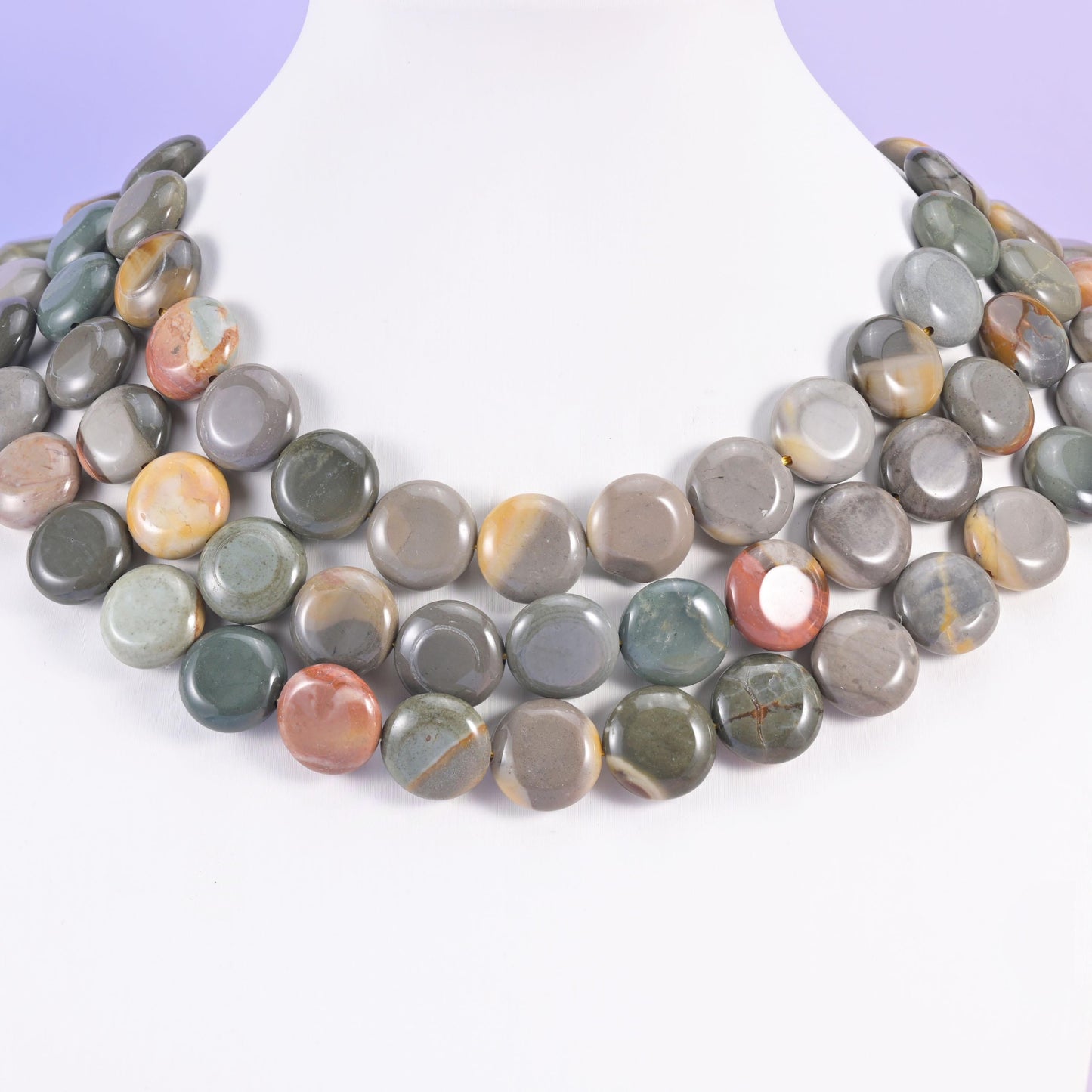 Three-strand picture jasper coin necklace on a white bust, grey and rust discs at the collarbone