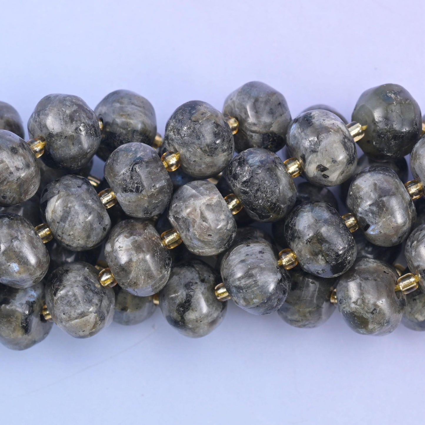 Close macro of grey labradorite pumpkin beads, silvery flecks scattered through the stone