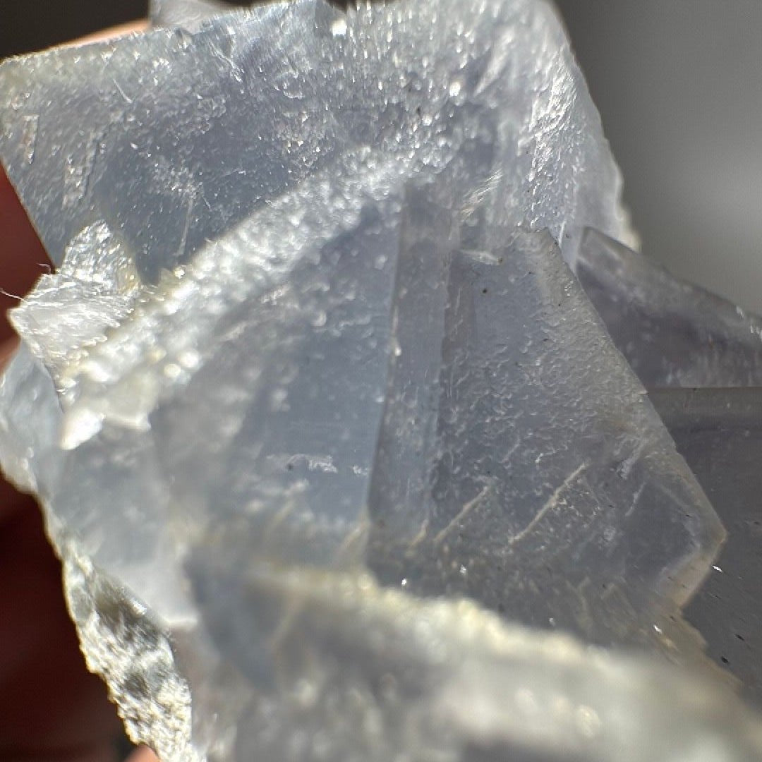 Extreme close-up where two fluorite crystal faces meet, with a frosted quartz seam running between them