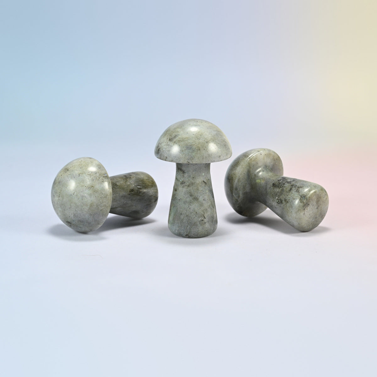Three 2 inch gray labradorite mushroom crystal carvings shown standing and lying, gray-green natural stone