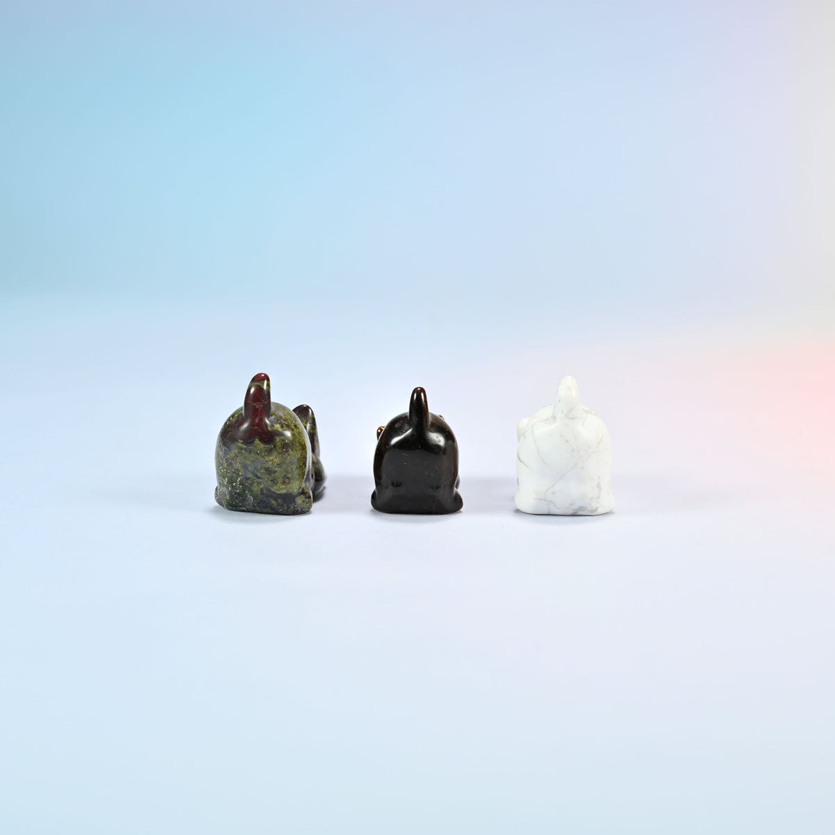 Back view of natural dragon bloodstone, tiger eye and white howlite yoga cat carvings showing their raised tails