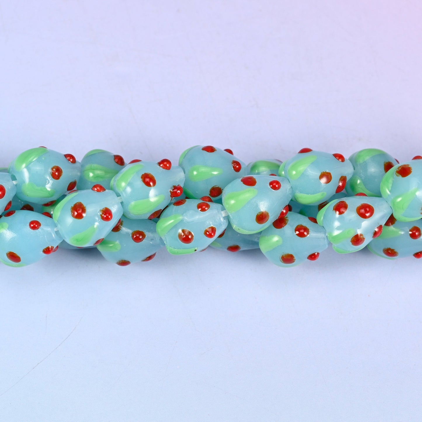 Man-made glass strawberry beads in light blue, red and green