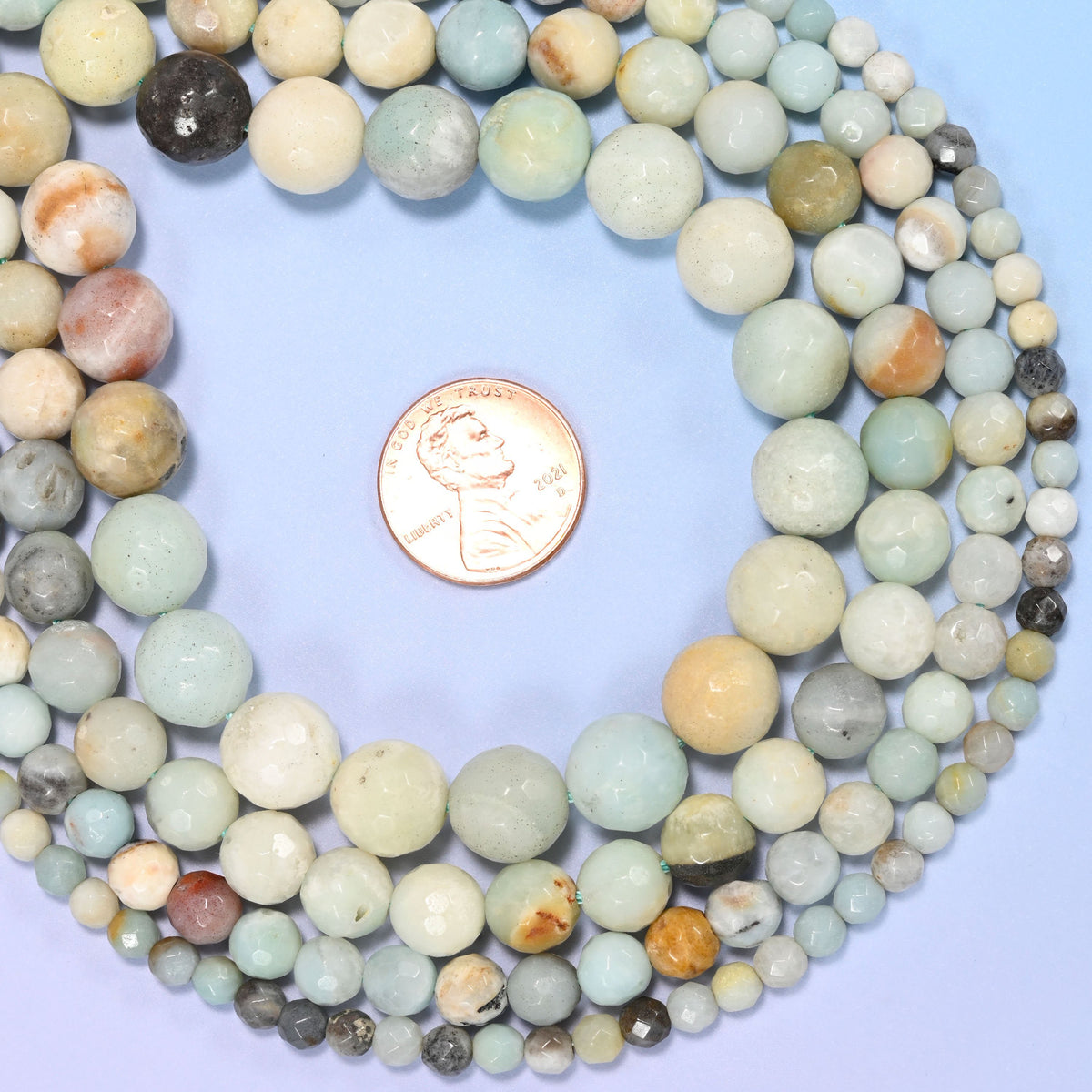 Multicolor amazonite faceted round beads in pale aqua and mint drifting into cream, sandy tan and grey tones, faceted so each bead picks up its own highlight.