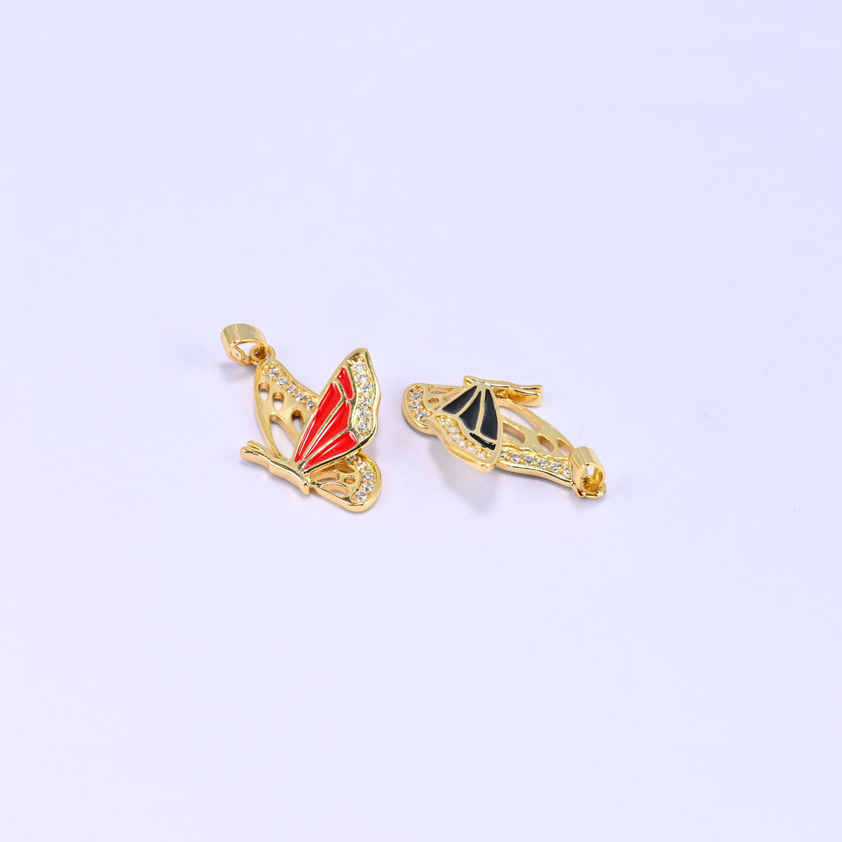 Red and black flying butterfly charm pendants together, the red charm upright and the black one resting on its side to show the wing profile.