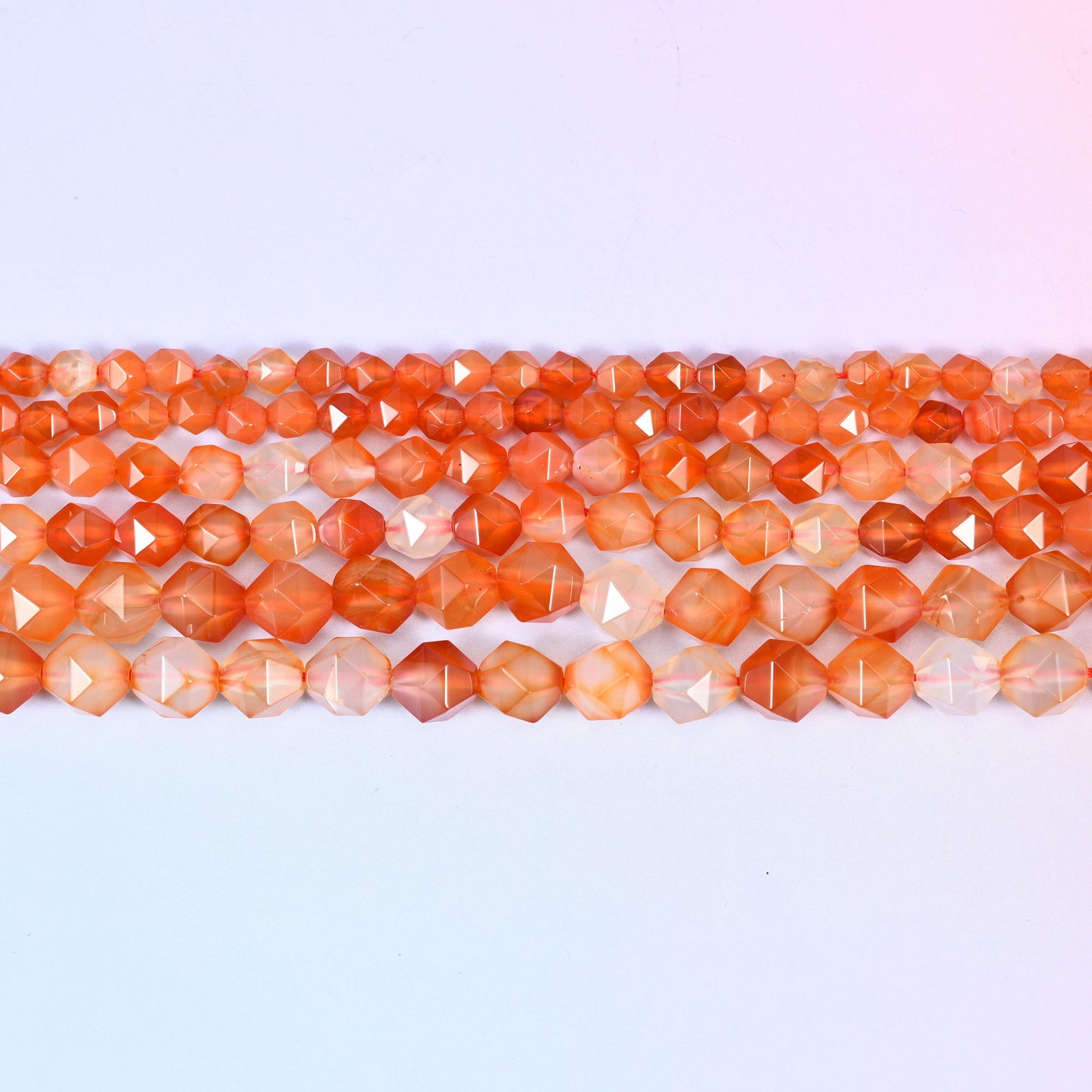 Orange Agate faceted beads in flat horizontal rows, orange shading to near-clear white, sold per 15.5 inch strand