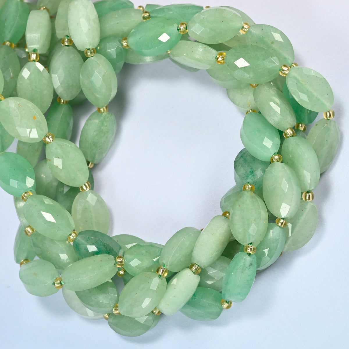 Green aventurine faceted flat oval beads coiled into overlapping loops, whole strands of soft green stone