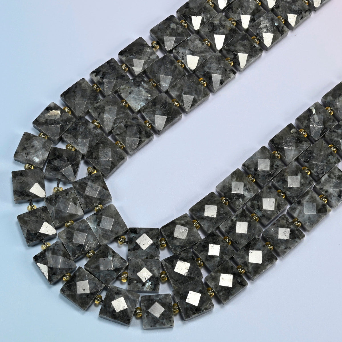 Natural black labradorite faceted flat square beads in several strands curved into a wide U, smoky dark gray stone with lighter specks