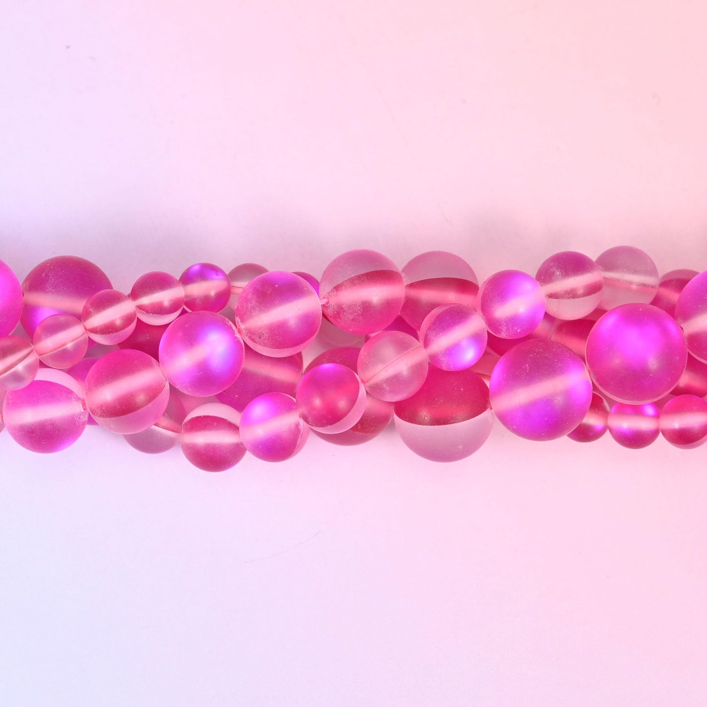 Frosted raspberry-pink glass beads with a soft sanded surface and aura core
