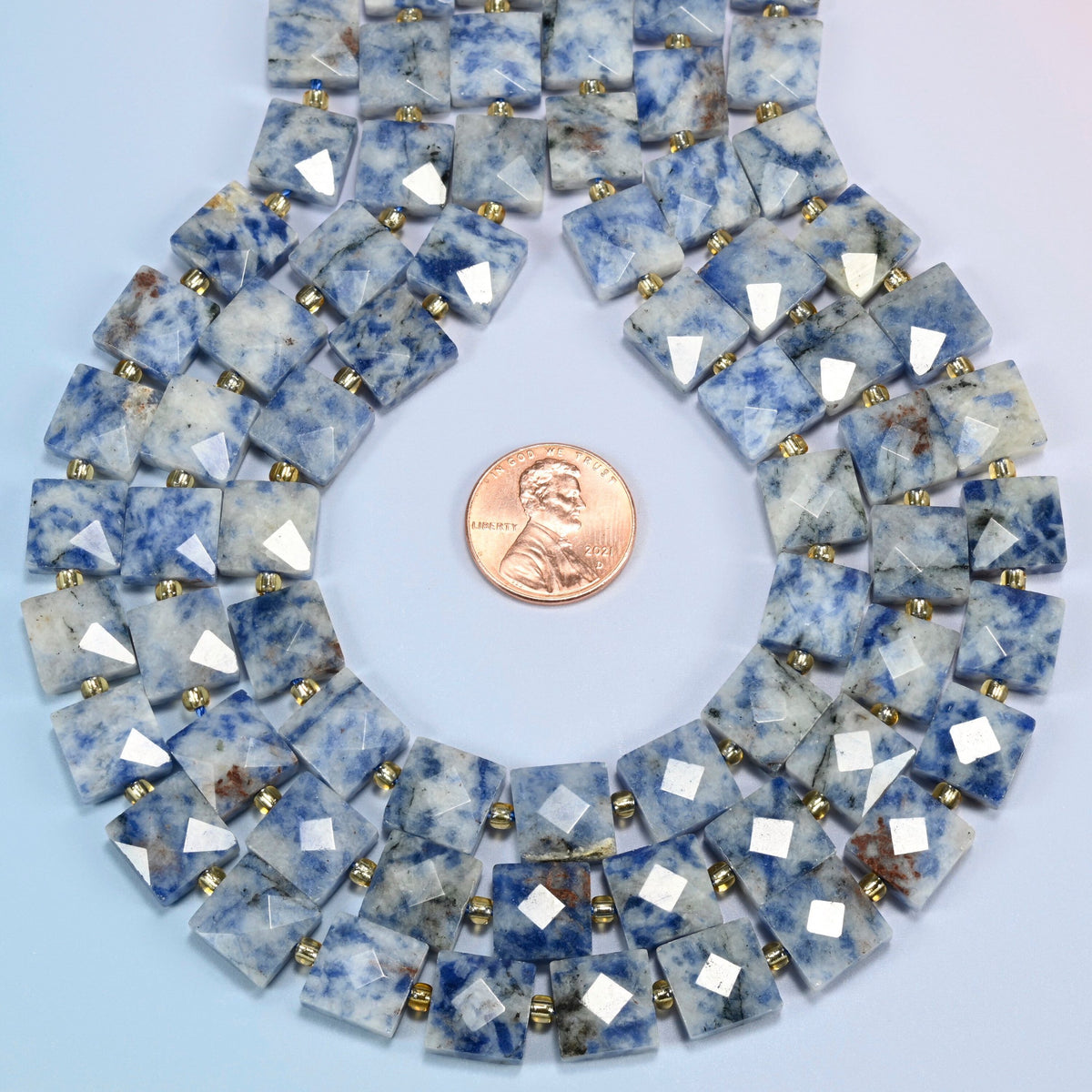 Natural blue spot jasper faceted flat square strands formed into a teardrop loop around a US penny for scale