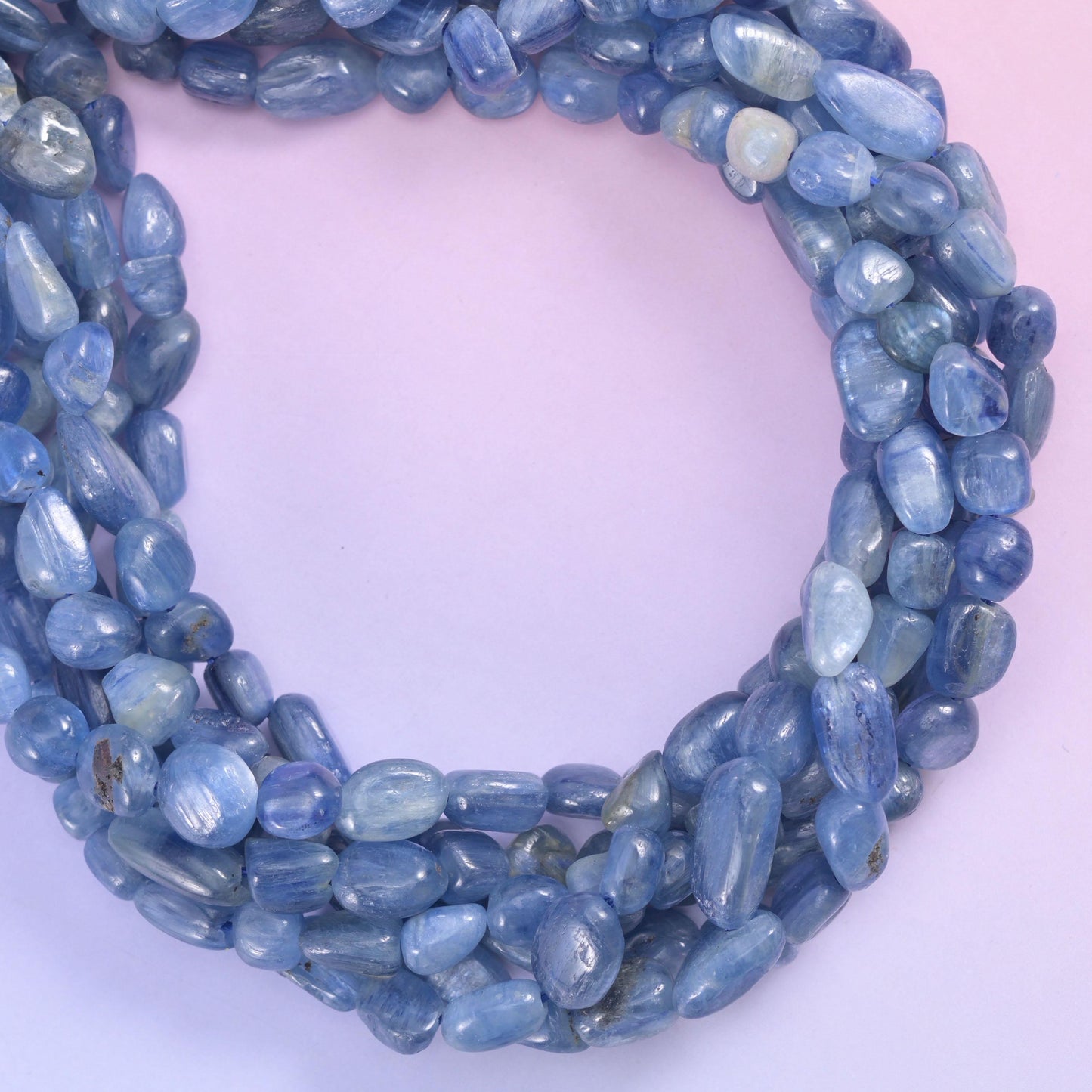 Kyanite nugget strands gathered into a rounded coil on a soft lavender surface
