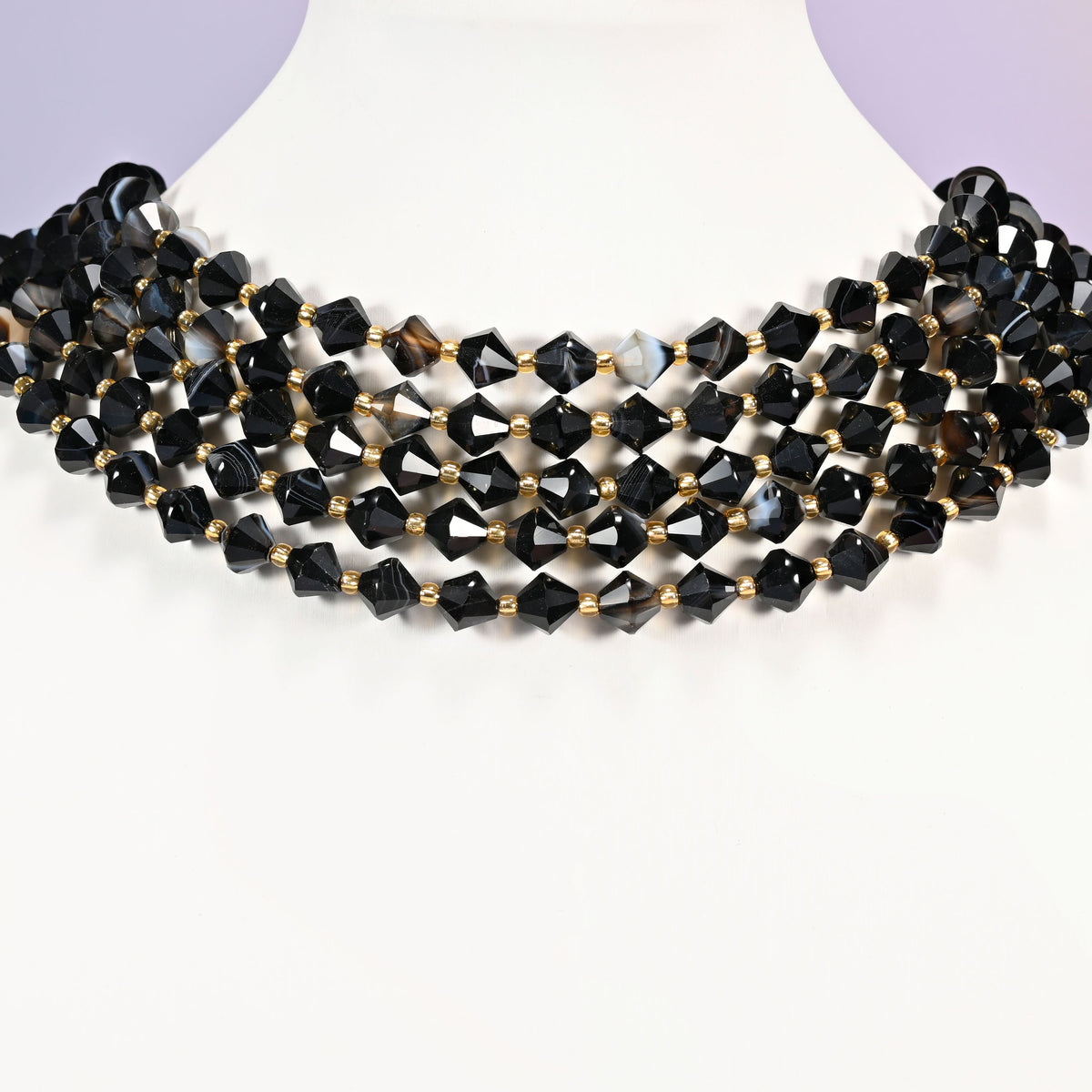 Dyed black strip agate bicone beads curved into a collar, pale gray and white stripes surfacing on some beads against the deep black.