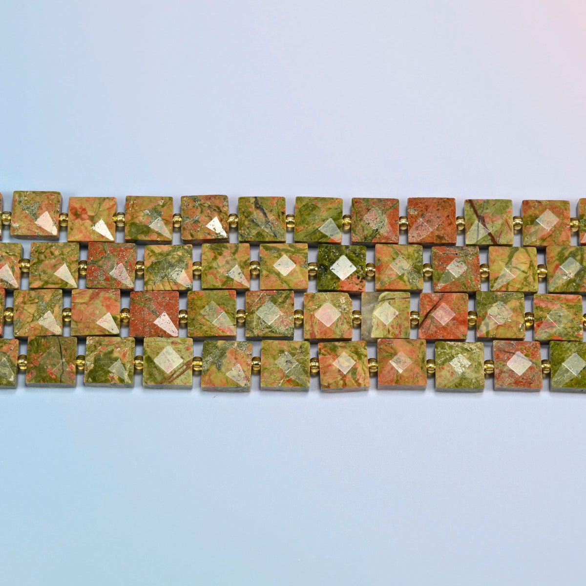 Several strands of natural unakite faceted flat square beads laid in straight rows