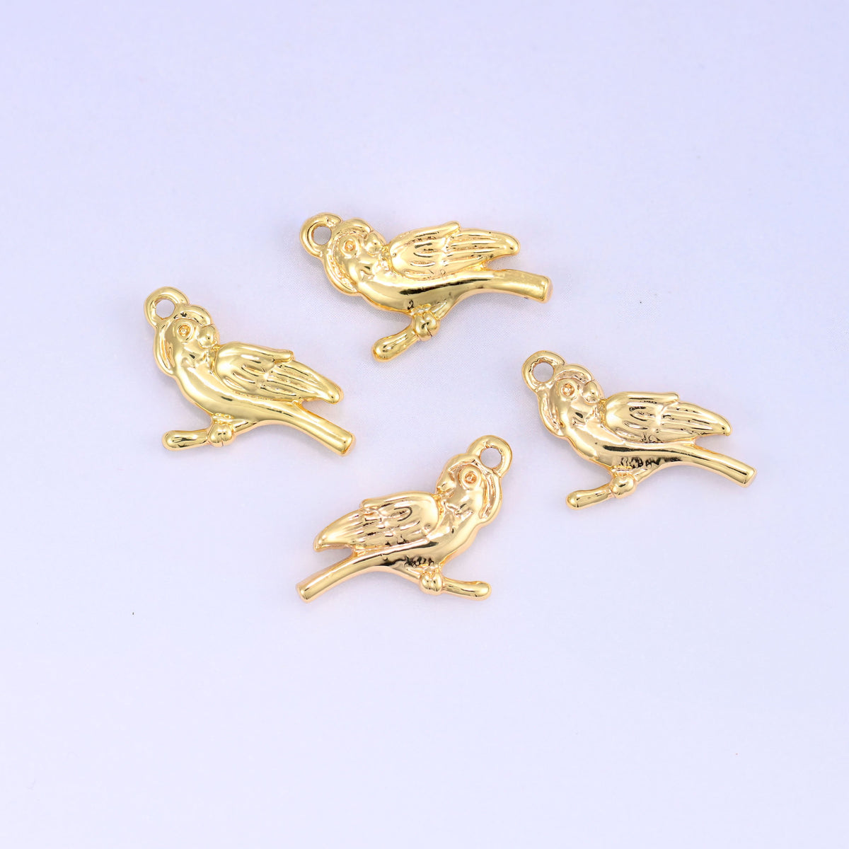 Small gold charms bird, five 18K gold plated charms scattered to show shape and polished finish