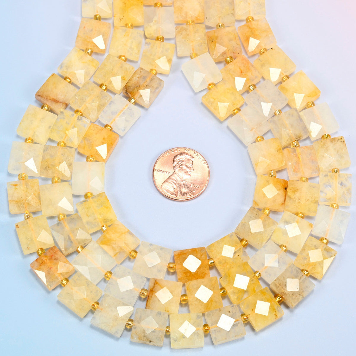 Natural golden healer quartz faceted flat square strands formed into a teardrop loop around a US penny for scale