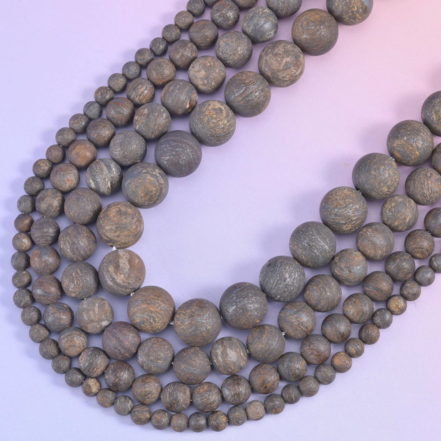 Two bronzite strands curving into a V, matte finish absorbing the light rather than reflecting it
