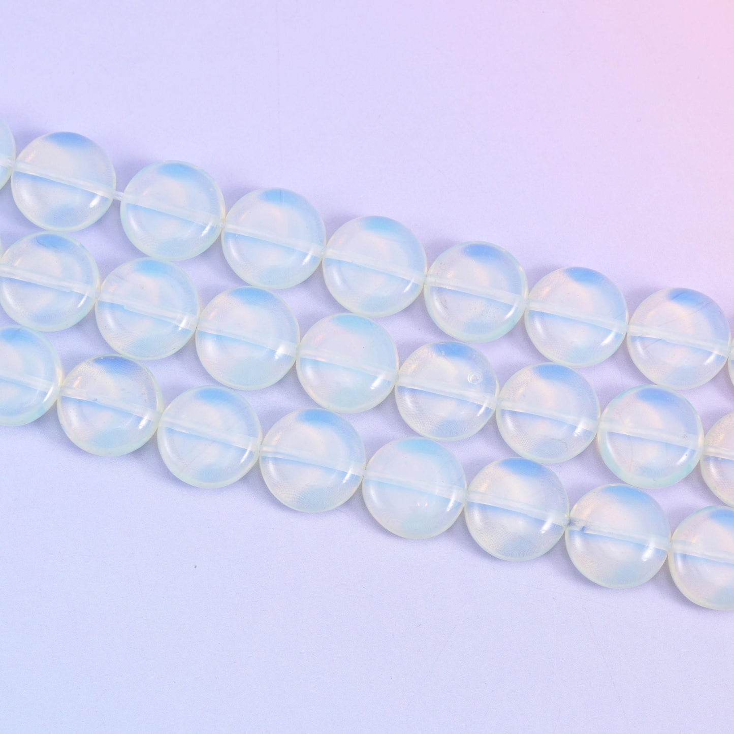 Opalite coin beads that shift from cool blue-white to a soft honey glow in light