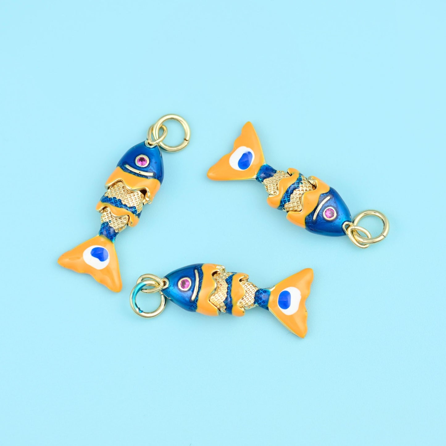 A slim fish built from jointed segments so the body flexes as it hangs: a deep cobalt enamelled head with a small ringed…