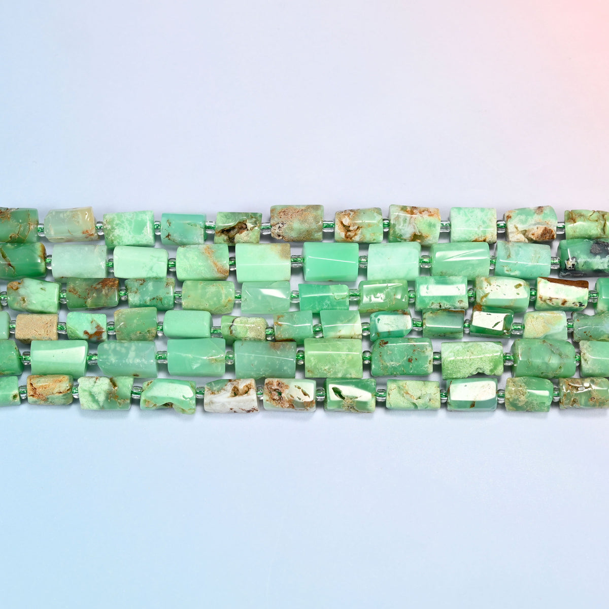 Several strands of Australian jade faceted tube beads laid in straight rows with light green seed bead spacers