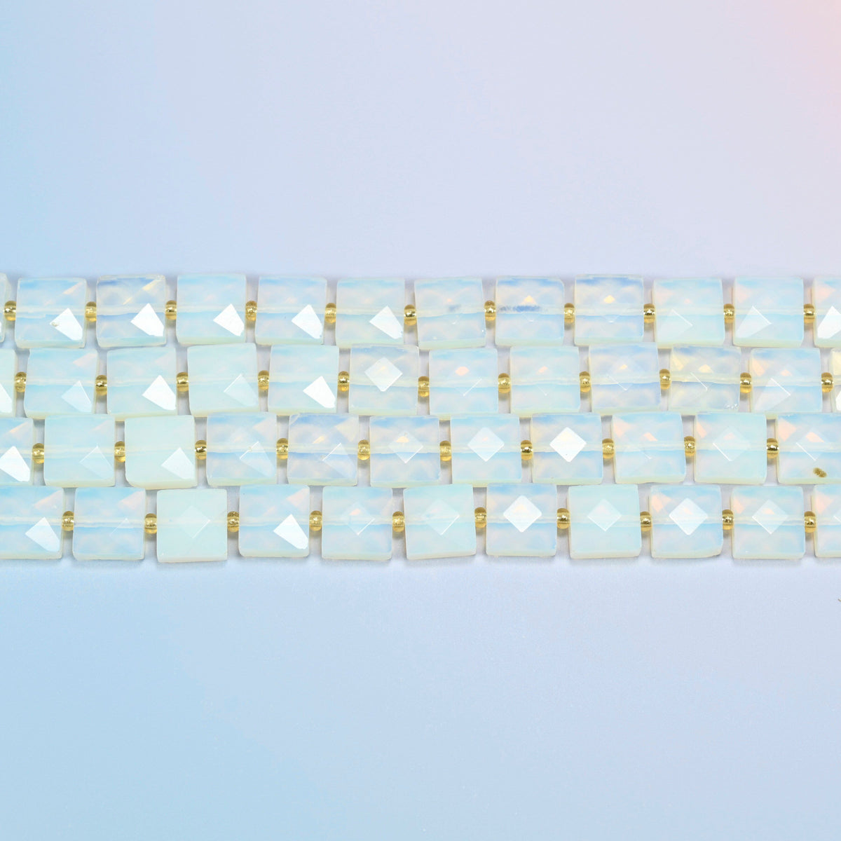 Several strands of opalite faceted flat square beads laid in straight rows