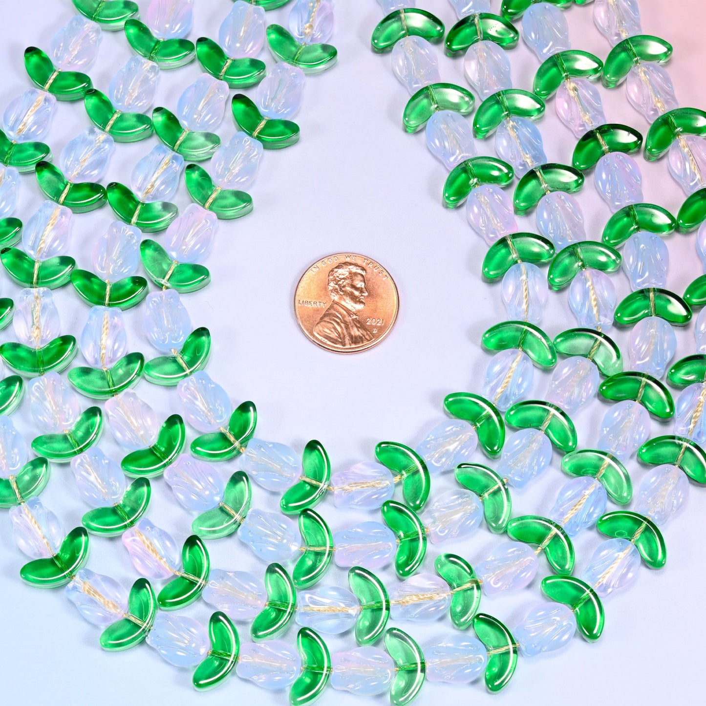 Close-up of a dense circular coil of white tulip and green leaf glass beads, showing the alternating flower and leaf pattern.
