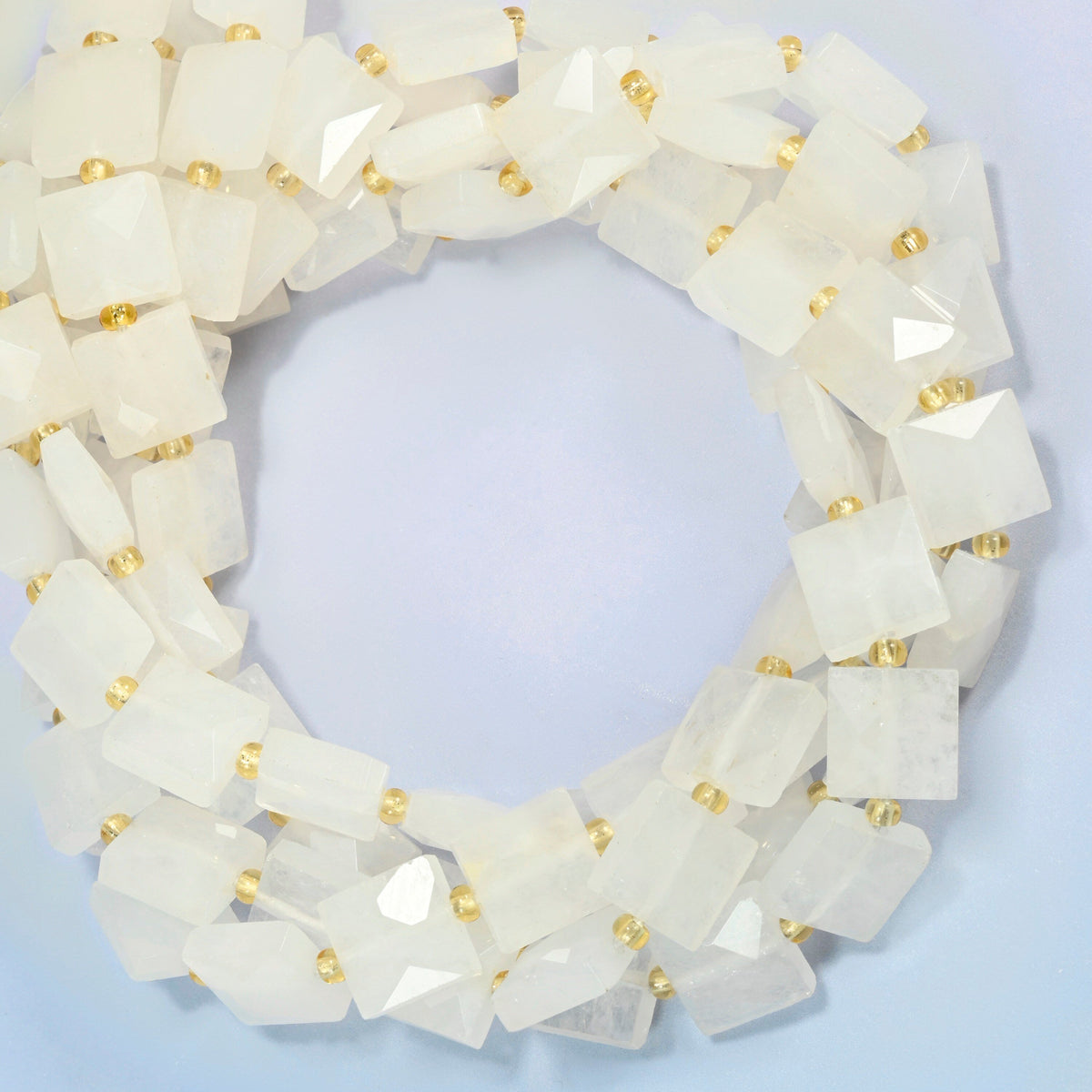 Clear quartz faceted flat square beads coiled into overlapping loops, whole strands of soft milky white stone