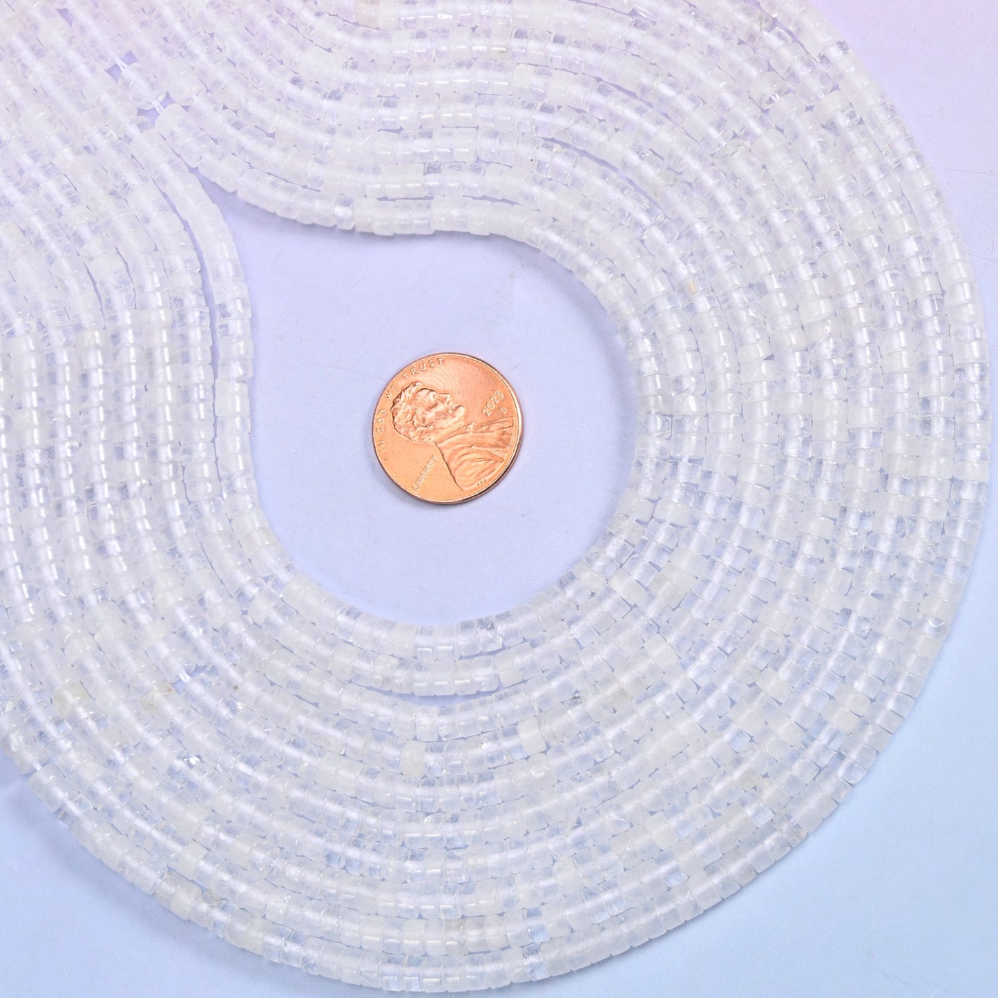 Translucent white through to almost water-clear, every disc polished until the flat face picks up the light. Roughly a hundred and eighty of them on a 15.5 inch strand.
