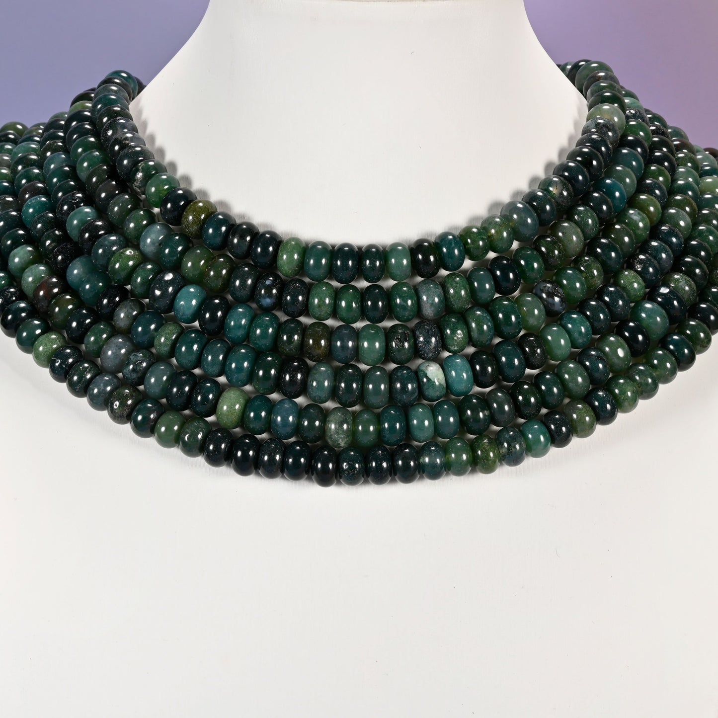Multi-strand Moss Agate necklace laid flat on a mannequin neck form against a lavender background.