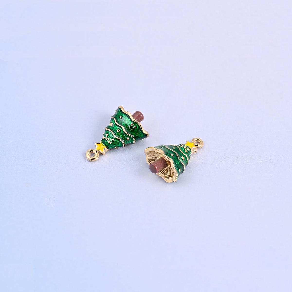 Two christmas tree charms angled to show the small gold ring at the top for easy attaching.