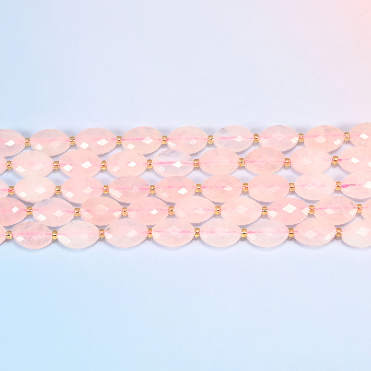 Several strands of rose quartz faceted flat oval beads laid in straight rows with gold seed bead spacers