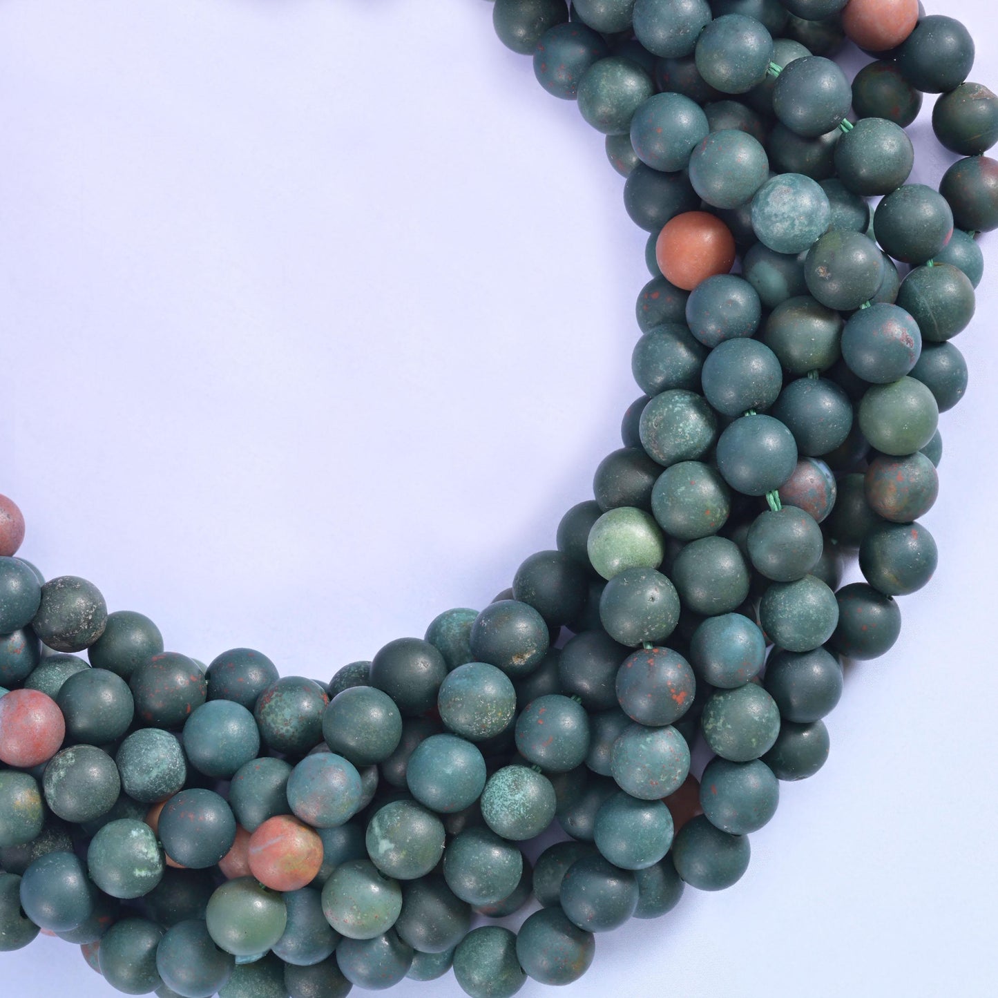 Deep pine and teal green with a dry frosted matte surface, broken up by occasional terracotta and rust-brown beads