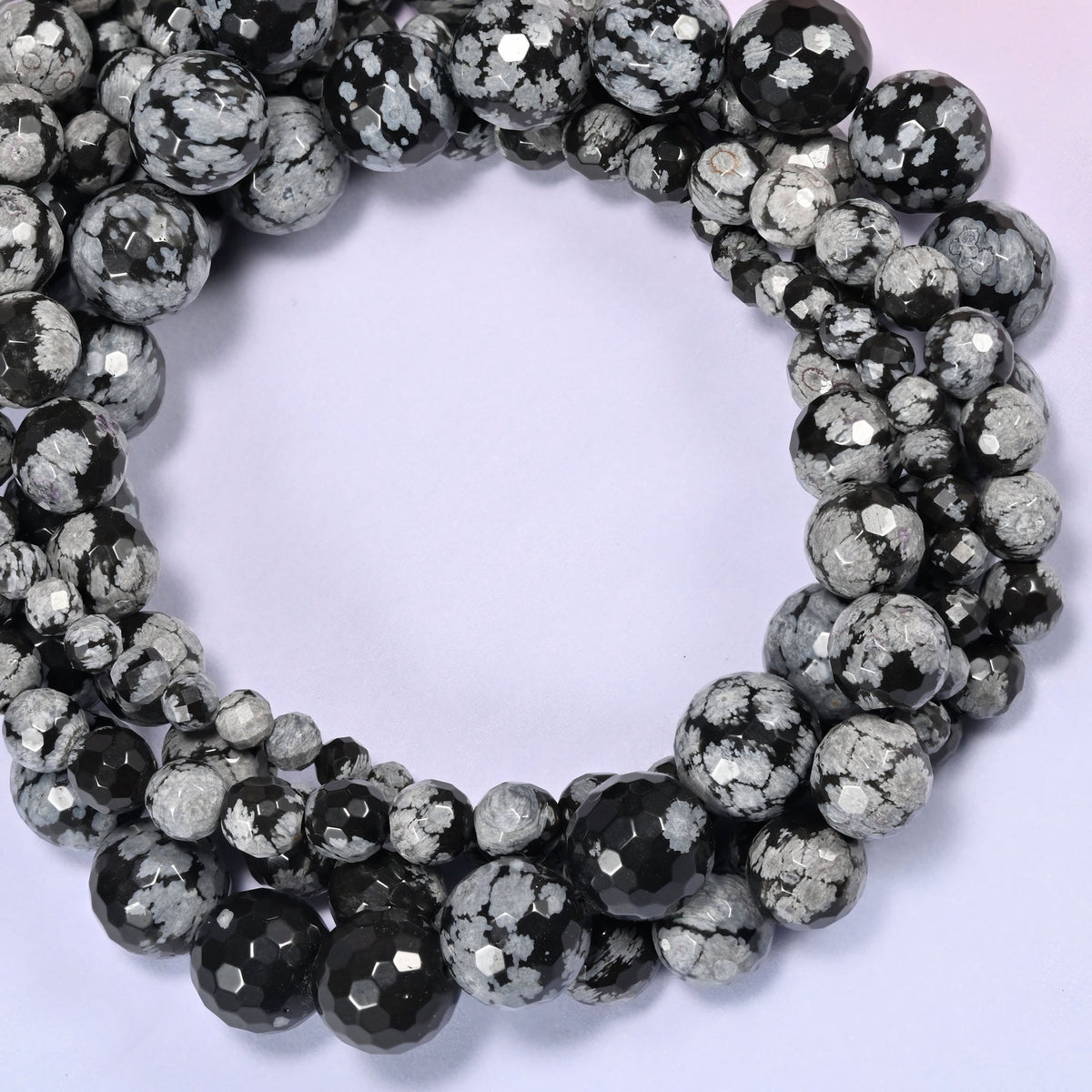 Snowflake Jasper faceted round bead strands coiled into a rounded loop, showing the graduating bead sizes from small to large.