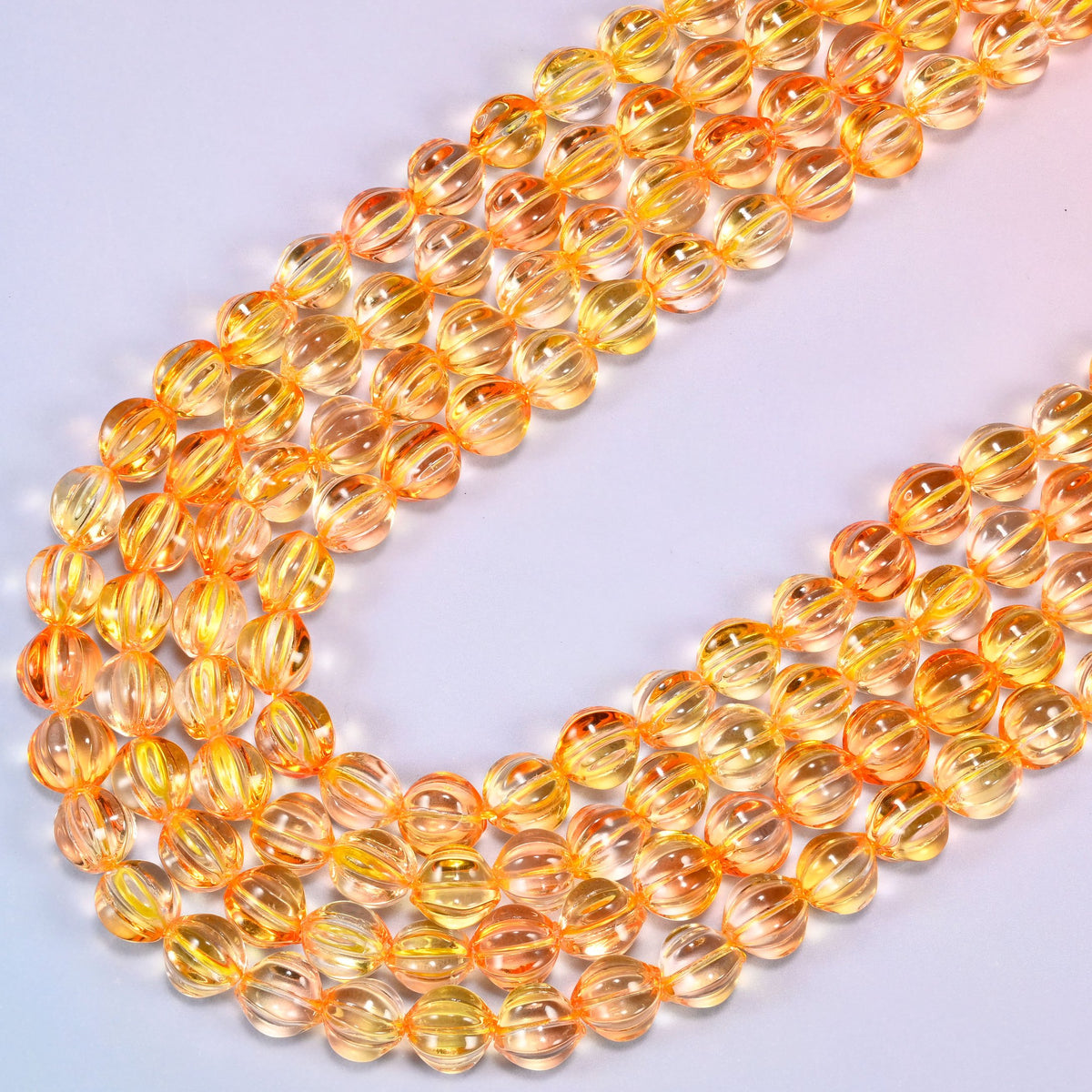 Yellow gold pumpkin glass beads coiled loosely, shown with a US penny resting on the strands for scale.