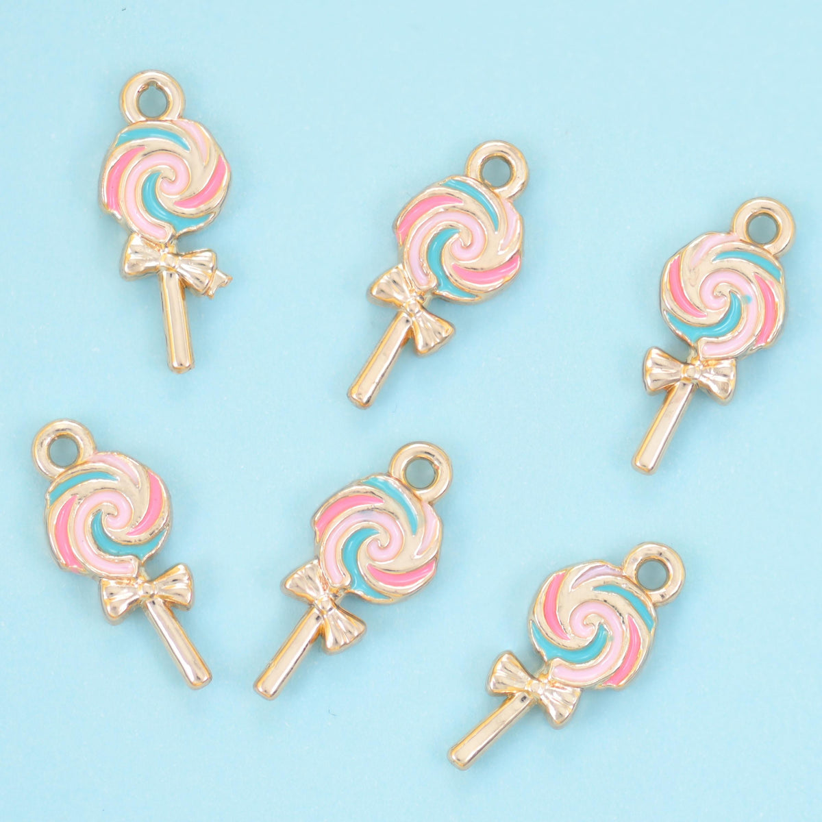 Enamel lollipop charms in a pink and white swirl, six charms with a small ring at the top.