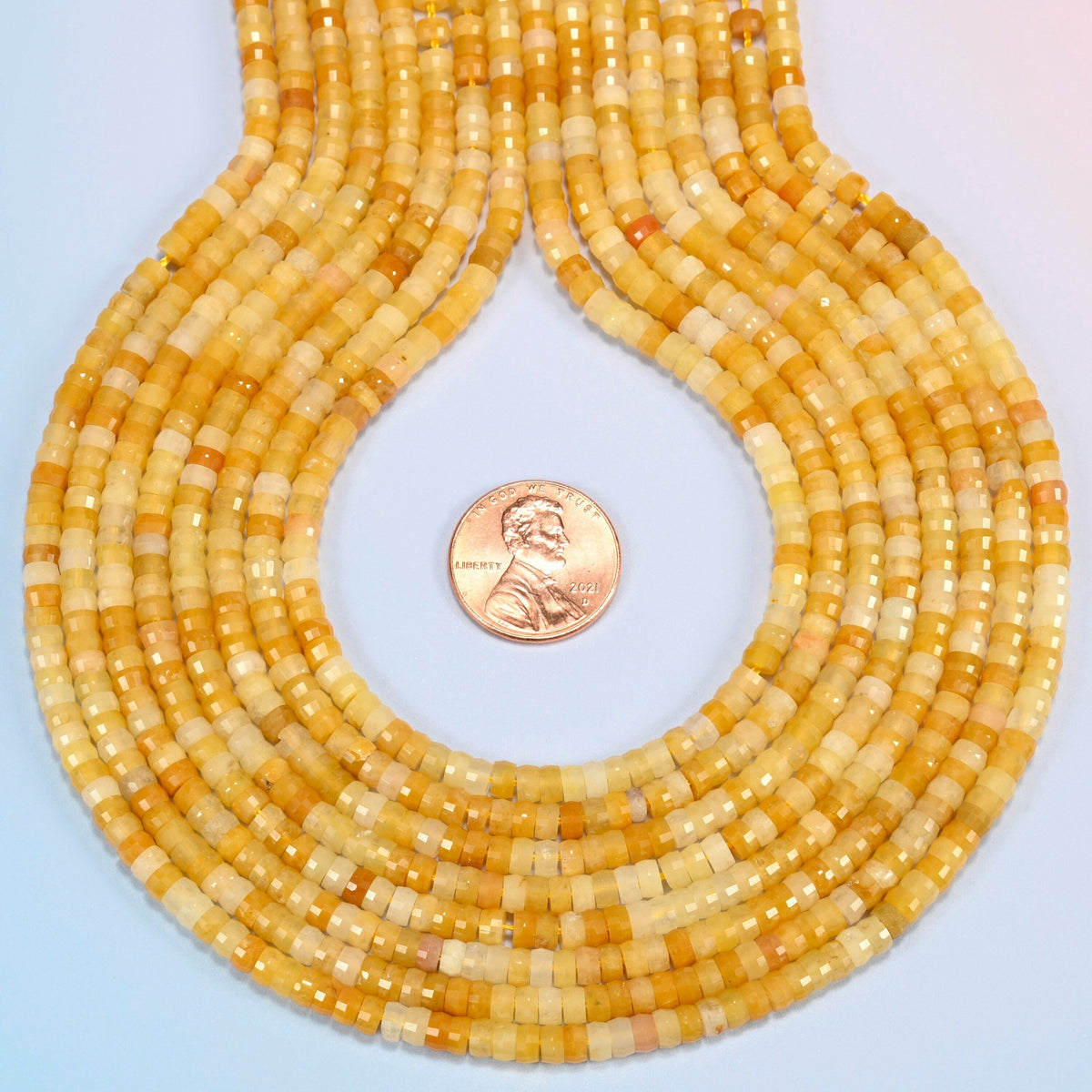Gold Silk Jade faceted heishi disc strands formed into a teardrop loop around a US penny for scale