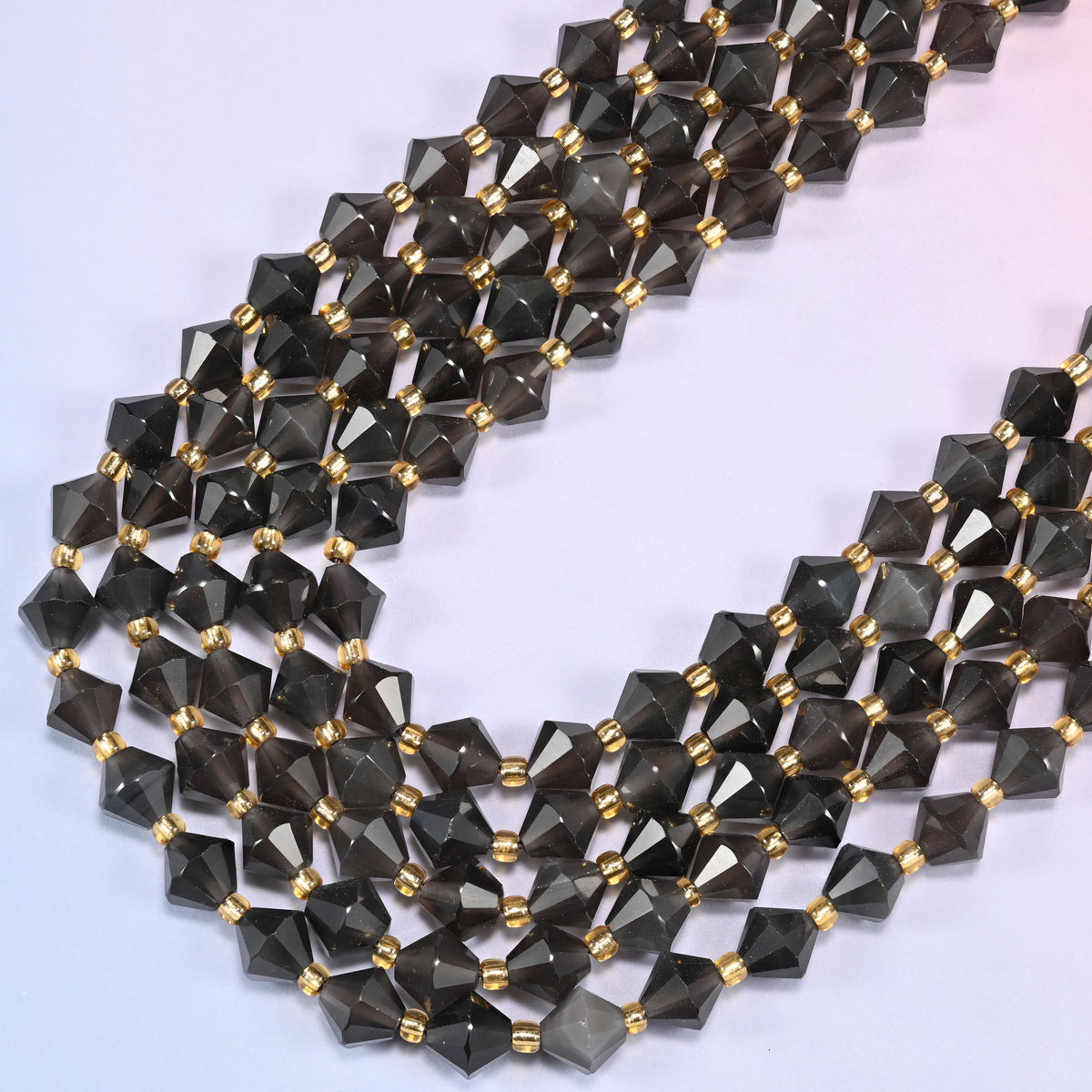 Ice Obsidian faceted bicone beads 8mm with gold-tone spacers, strand draped in a loose diagonal curve